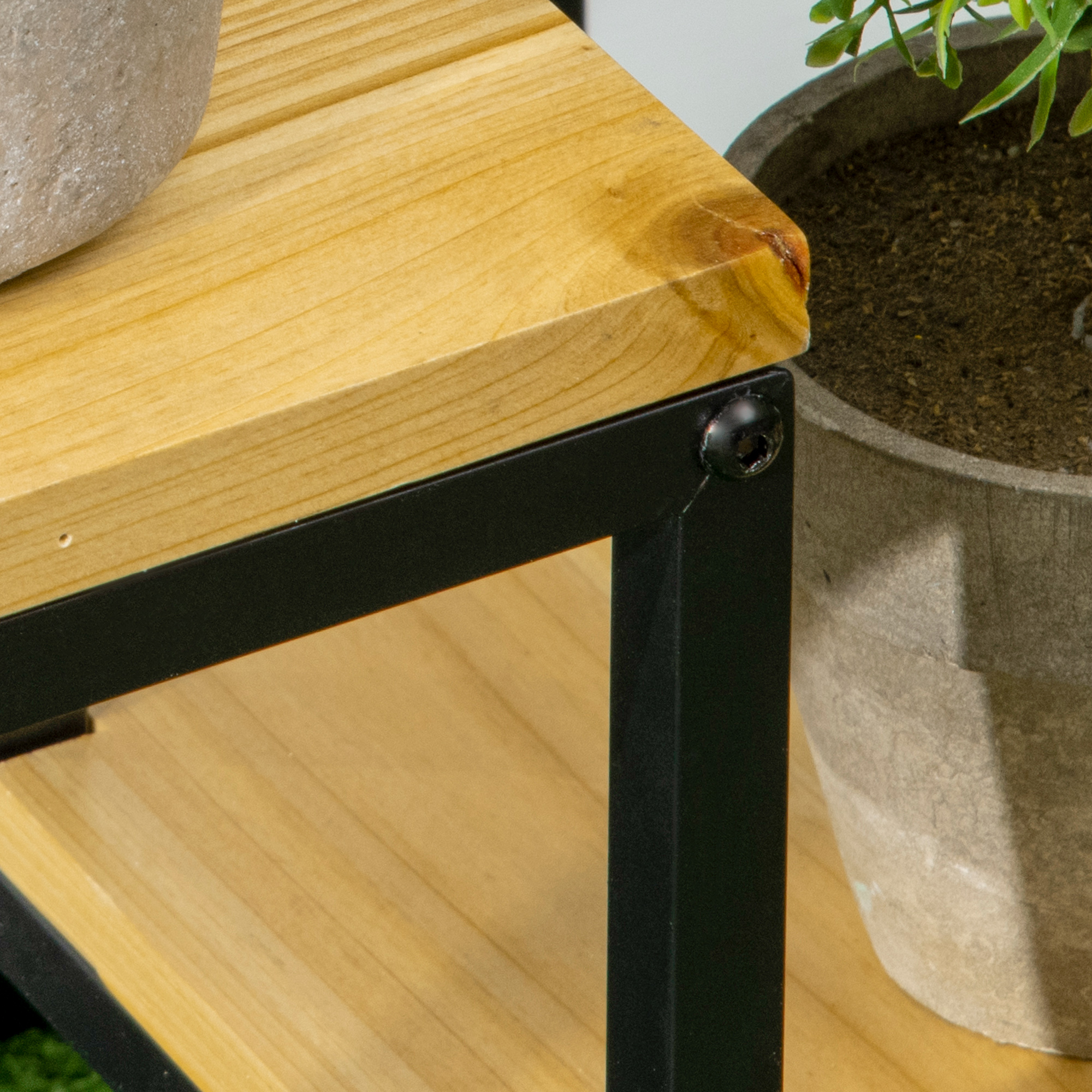 Primo piano di un angolo di mensola in legno con telaio in metallo nero e pianta in vaso.