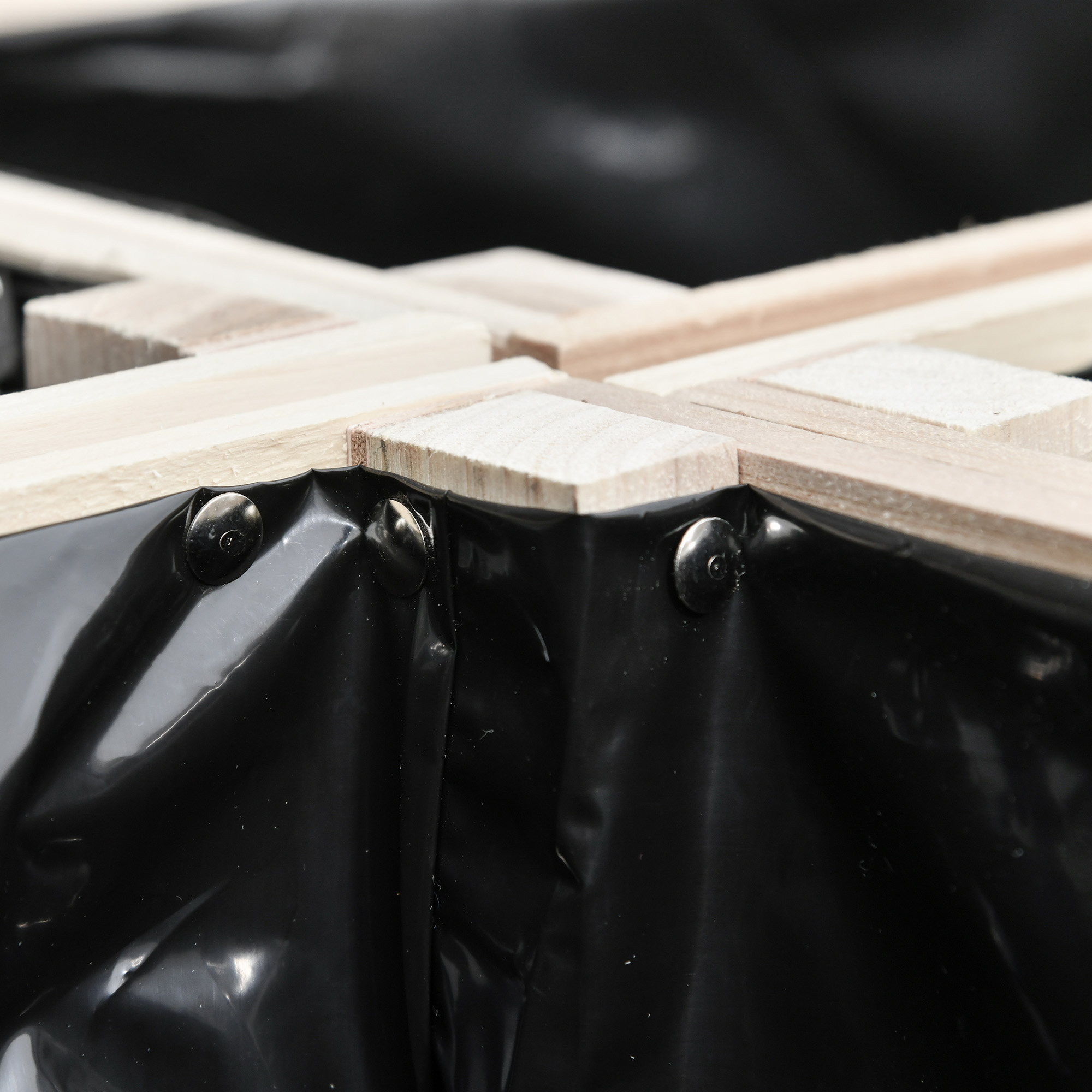 Primo piano della costruzione di una fioriera in plastica nera e legno.