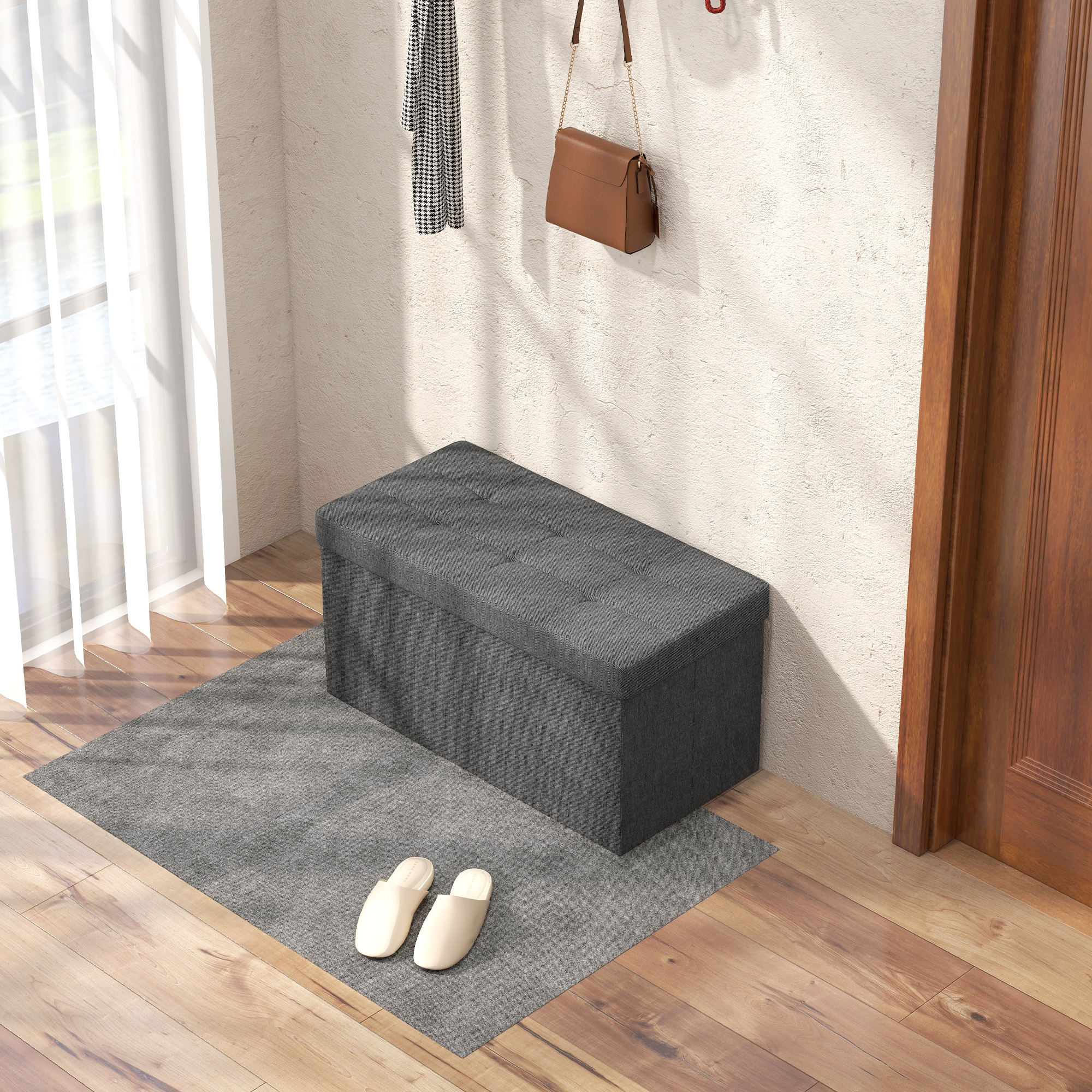 Un otomán de almacenamiento de tela gris con tapa, una alfombra, zapatillas y una puerta al fondo.