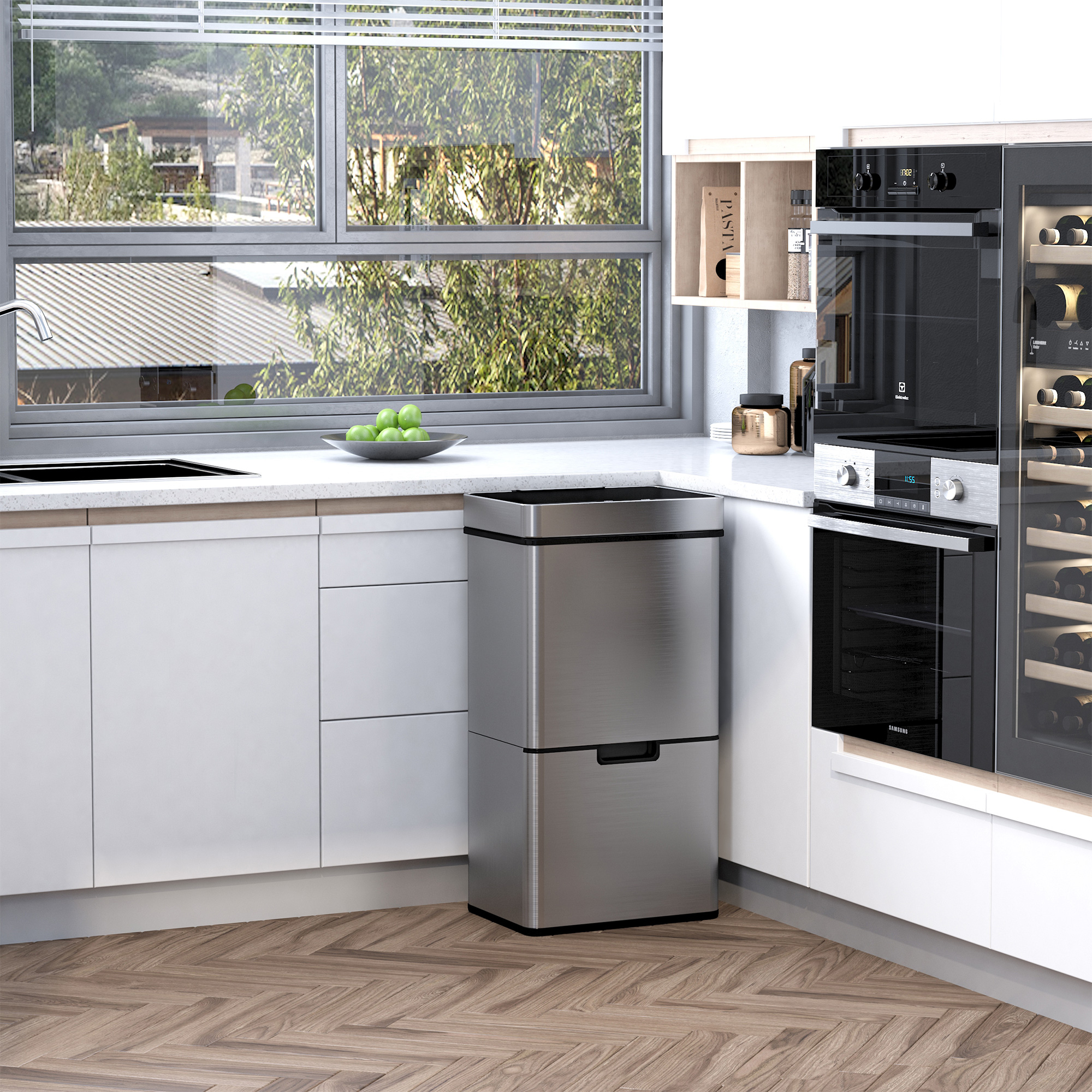 Bidone della spazzatura argentato in cucina. Ha due scomparti. La cucina ha mobili bianchi.