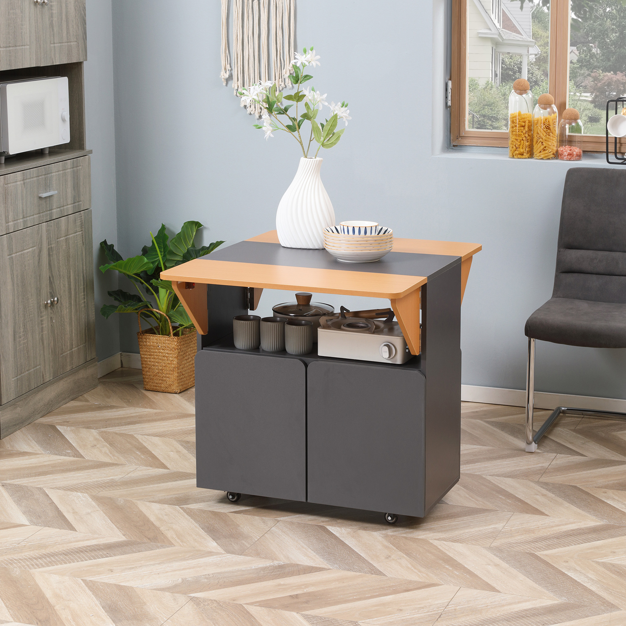 Un'isola cucina con piano in legno e base grigia. C'è un vaso bianco e un forno a microonde.