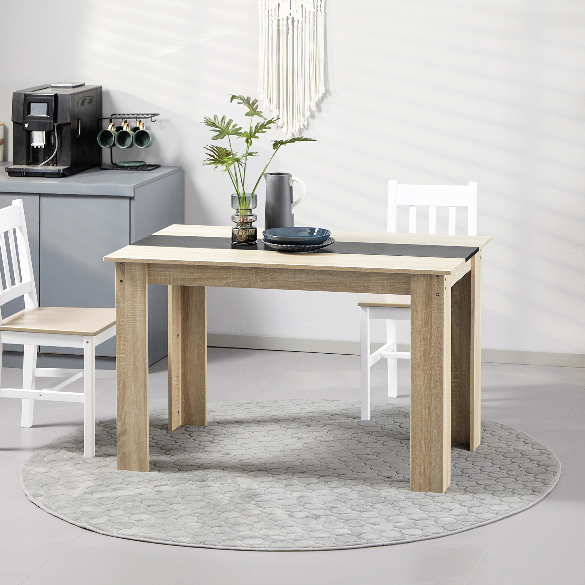 Tavolo da pranzo con sedie, macchina da caffè e decorazioni. Tappeto rotondo visibile.