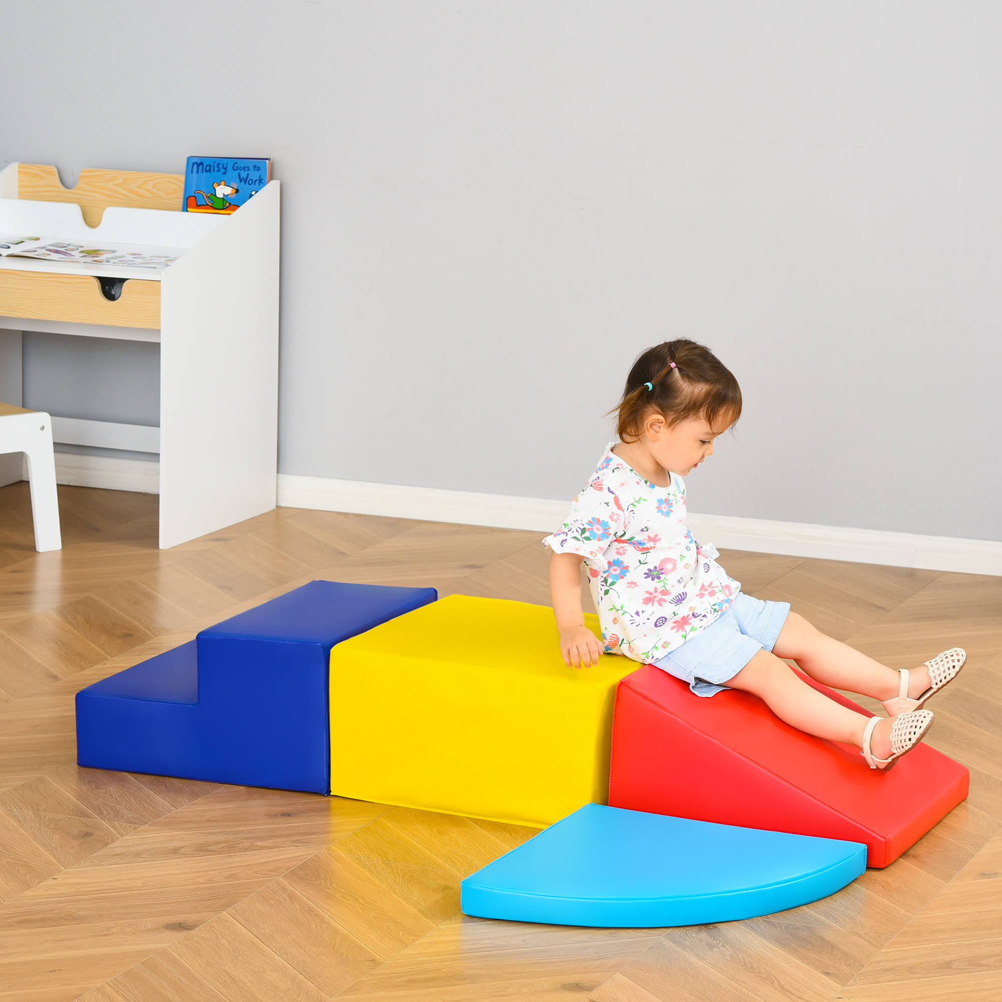 Un bambino siede su blocchi di schiuma colorati disposti come gradini e una rampa.