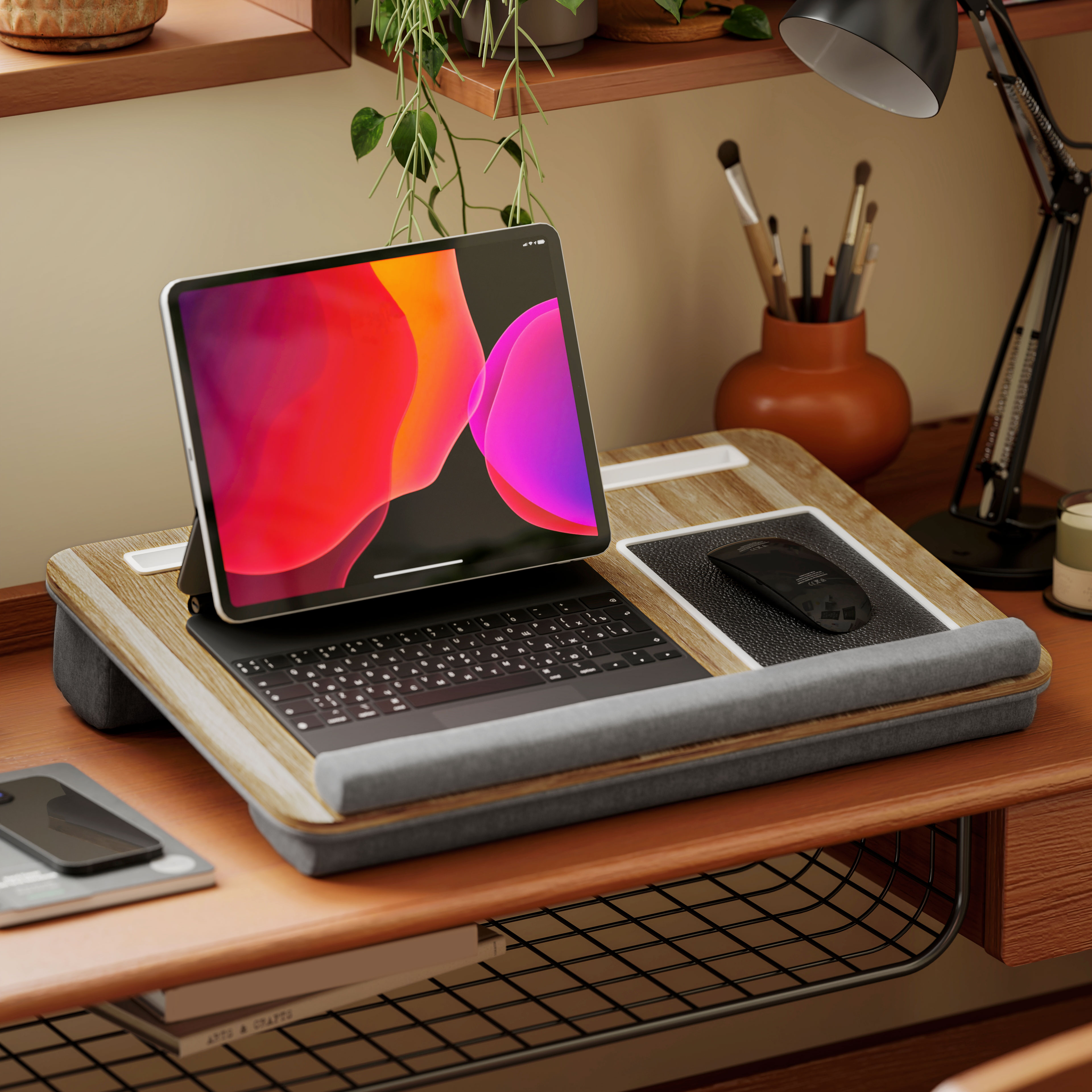 Portátil en escritorio de madera con ratón y teclado. Lámpara y teléfono también presentes.