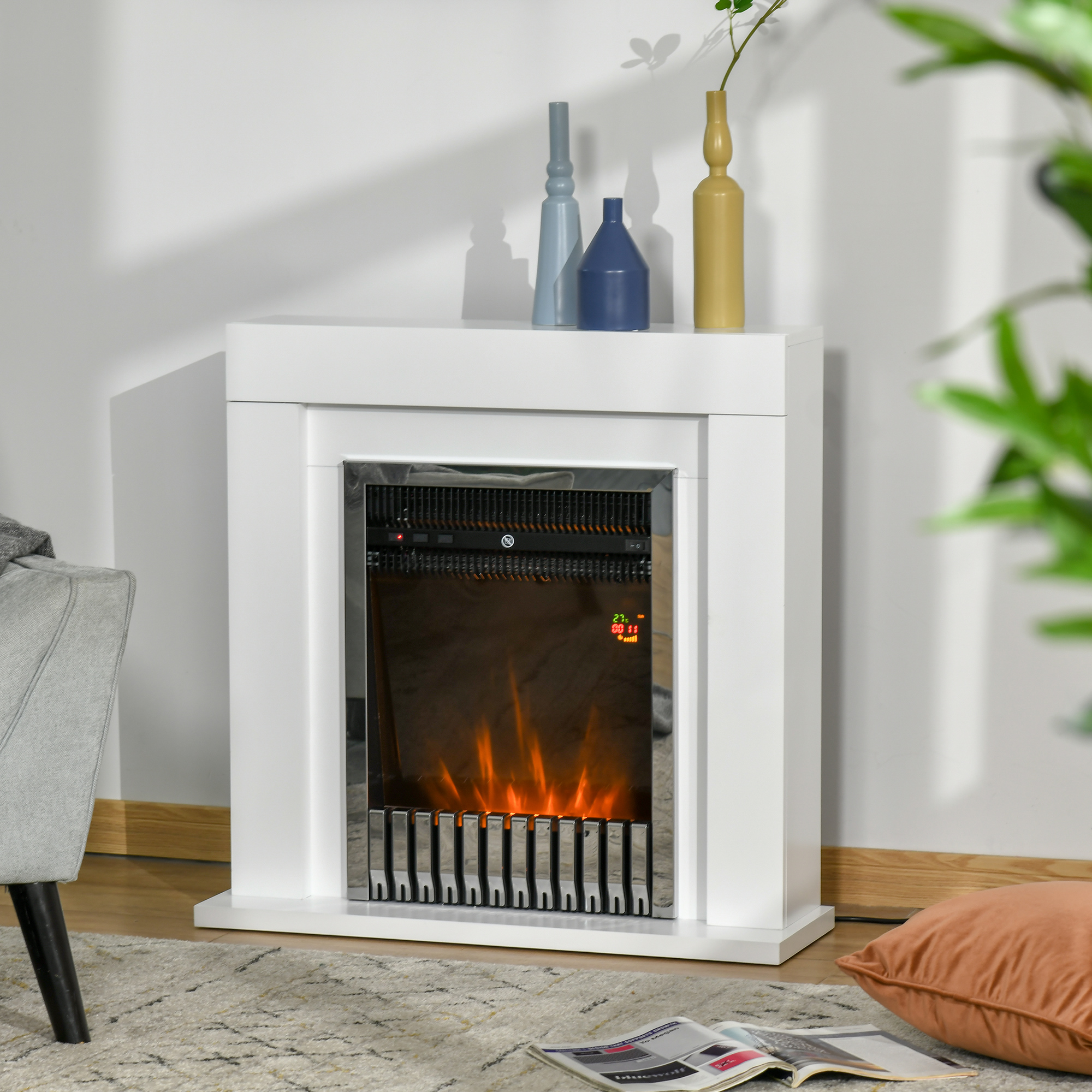 Caminetto elettrico bianco con fiamme, vasi e un tappeto. Un telecomando è posizionato sul caminetto.