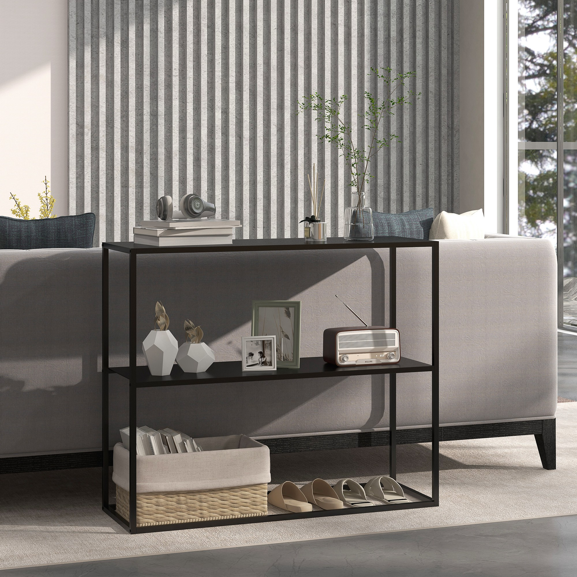 Scaffale in metallo nero con oggetti decorativi sopra. Scarpe, un cestino e altro sullo scaffale inferiore. Divano sullo sfondo.