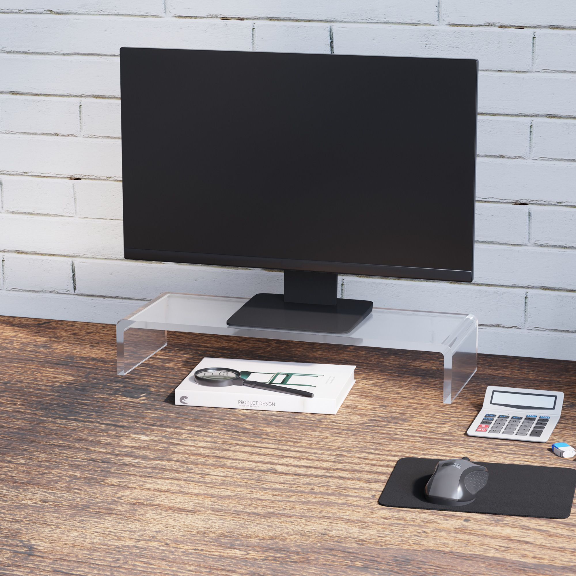 Un monitor su un supporto trasparente su una scrivania di legno. Libro, lente d'ingrandimento e mouse.