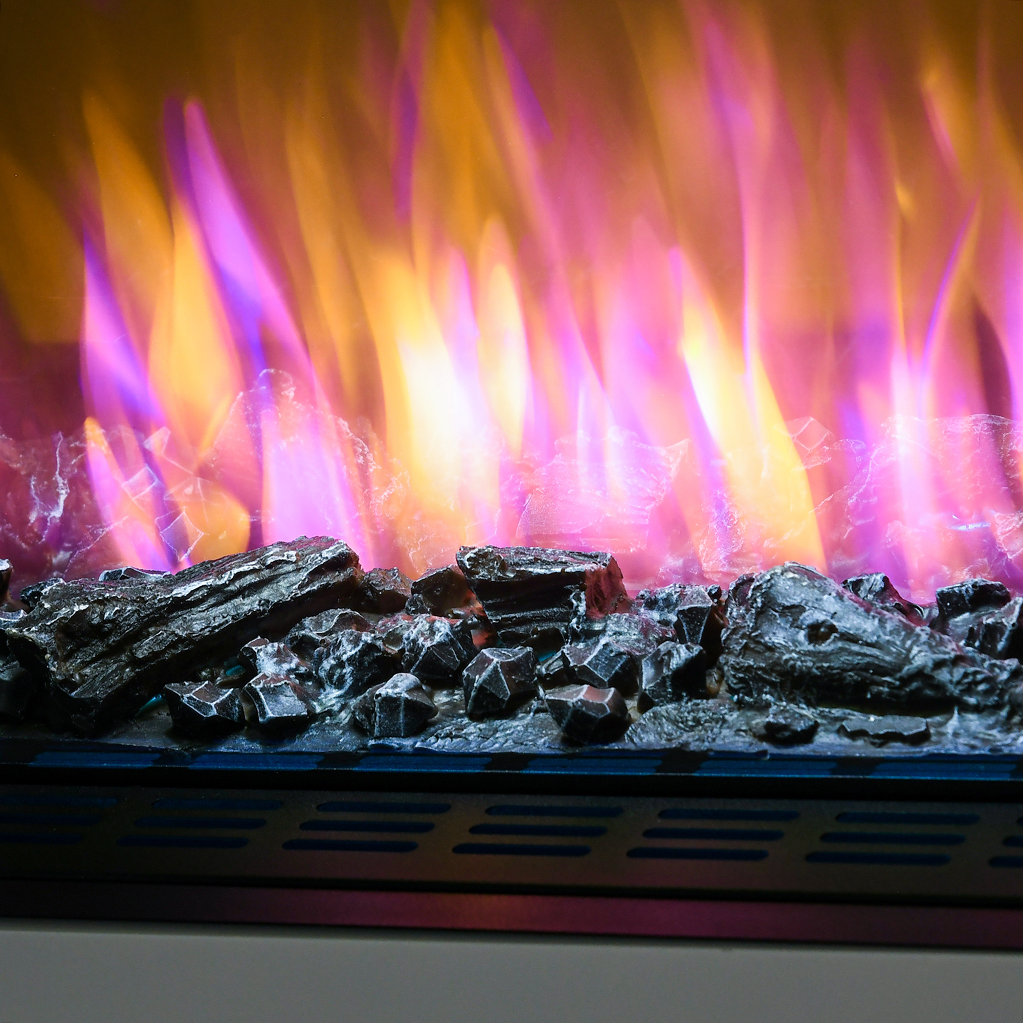 Primo piano di un caminetto con fiamme vibranti in tonalità viola, arancione e giallo, e rocce scure.