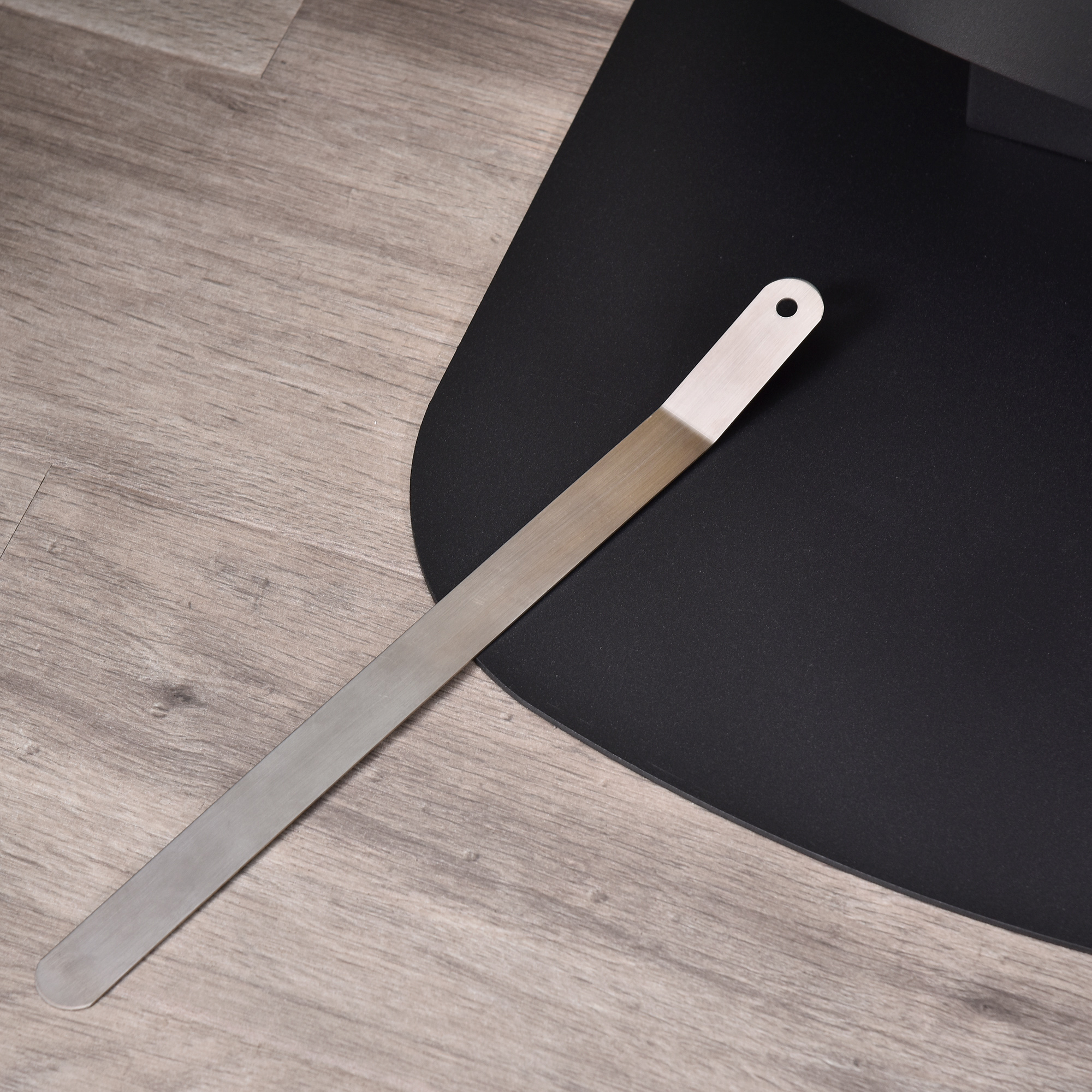 Una spatola di metallo su un pavimento di legno vicino a una base nera.