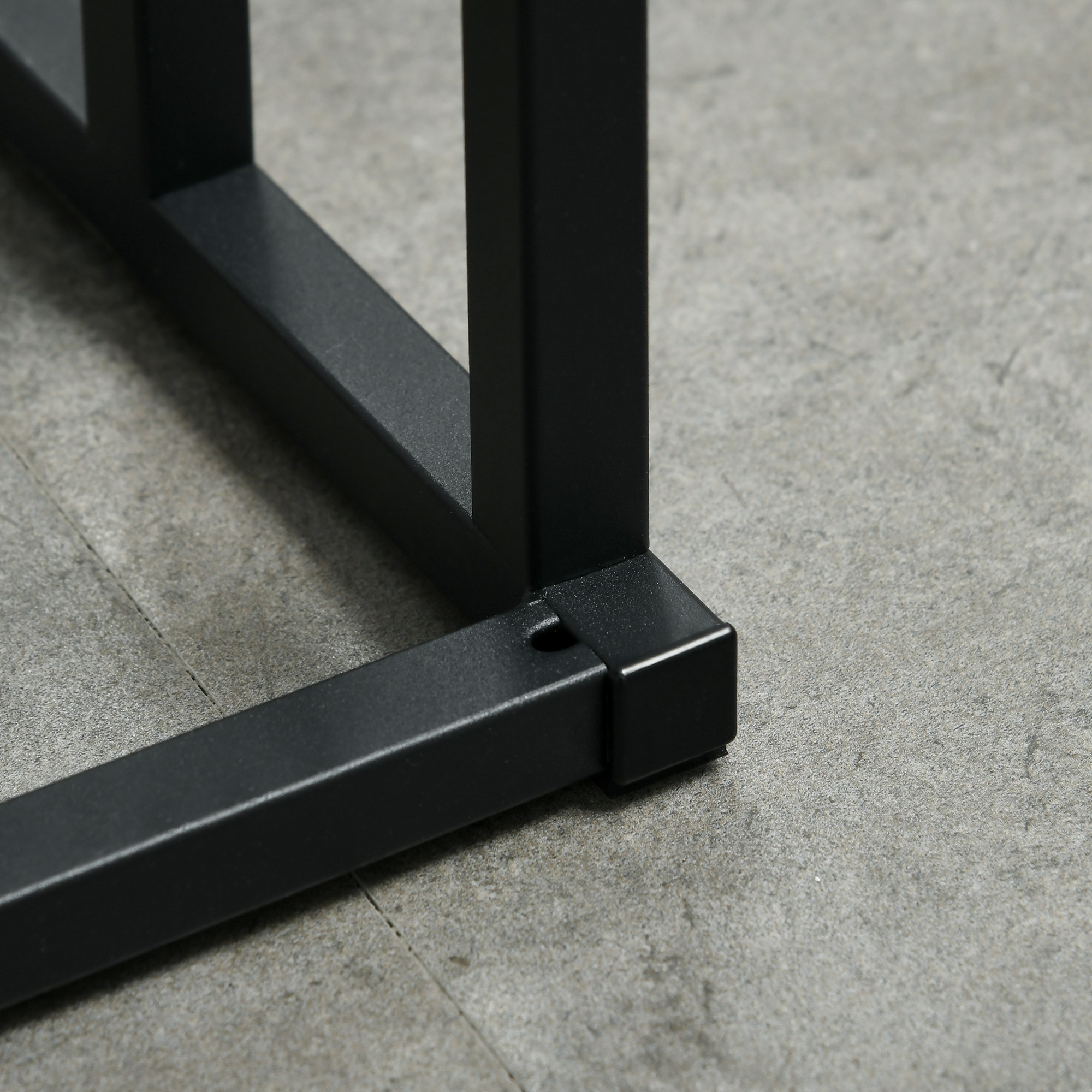 Primo piano dell'angolo di un telaio in metallo nero su pavimento in cemento grigio.
