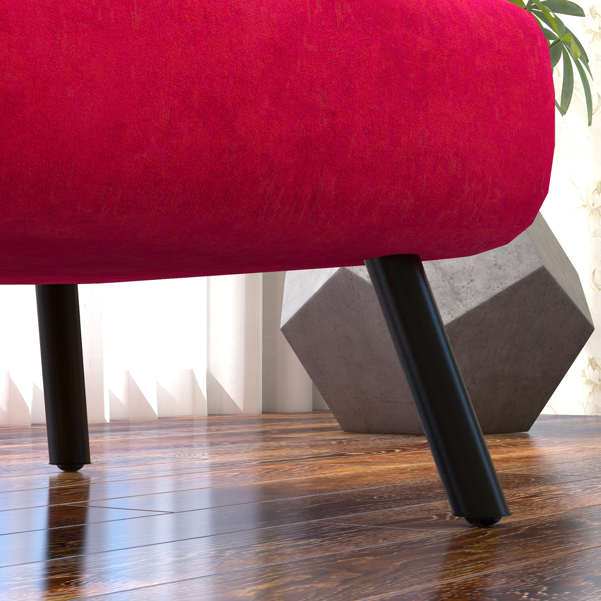Primo piano di divano rosso curvo con gambe nere su pavimento in legno, con un cubo sullo sfondo.