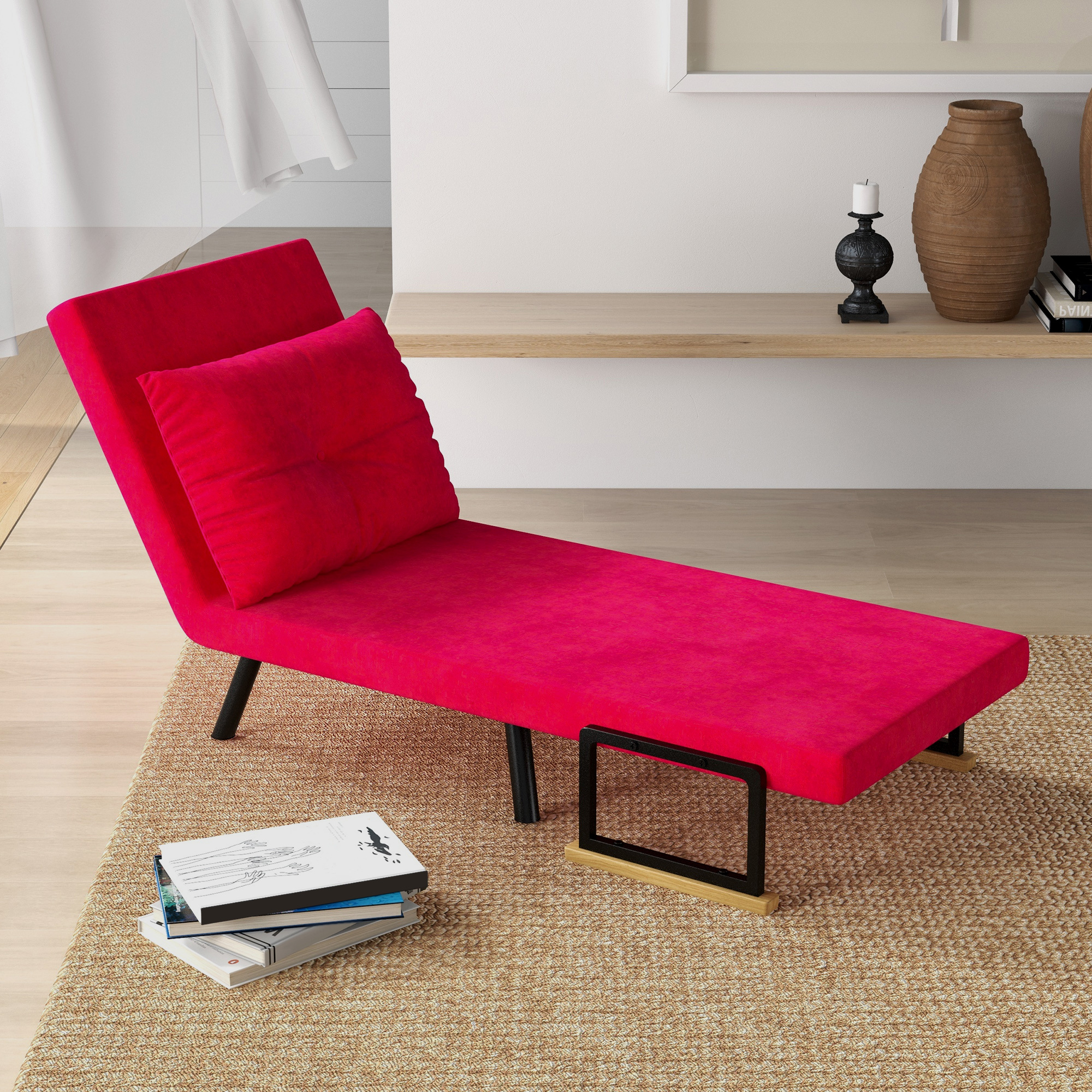 Una chaise longue rossa con cuscino, libri e una cornice decorativa in una stanza ben illuminata.