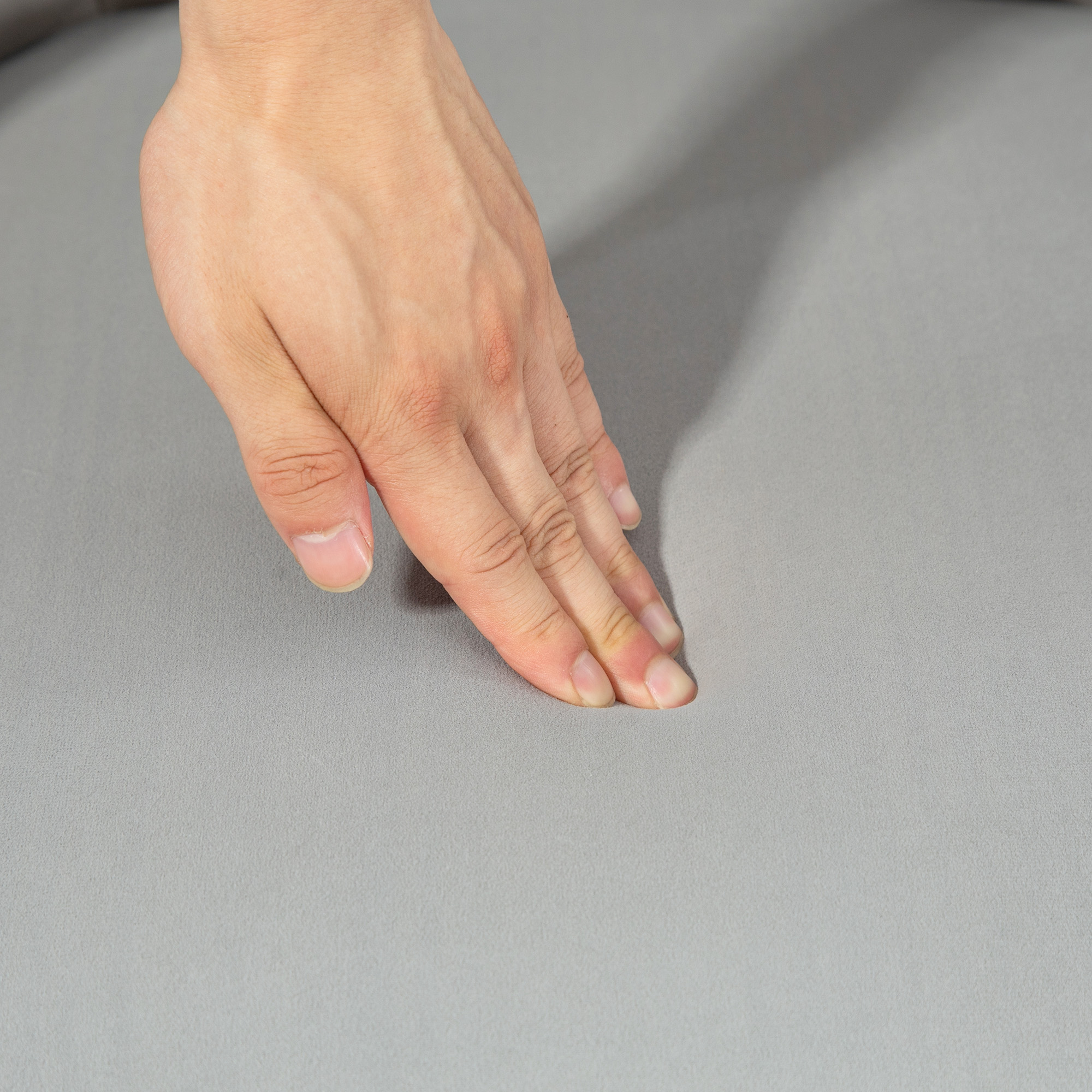 Una mano preme su una superficie liscia e grigia. Le dita sono leggermente divaricate.