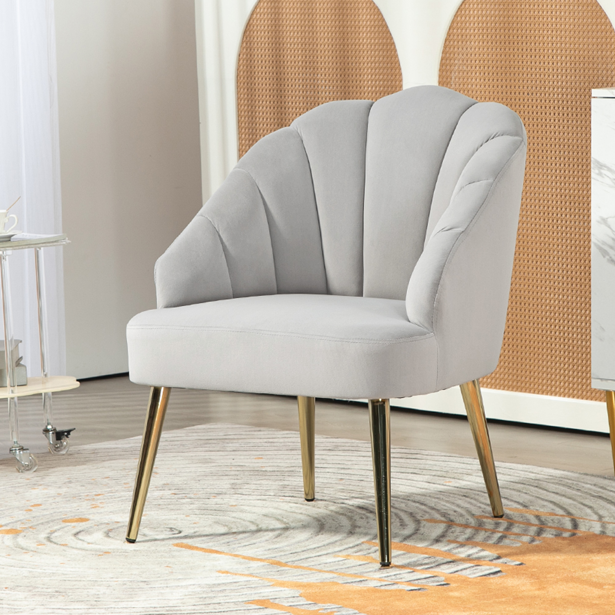 Una sedia grigio chiaro, simile al velluto, con gambe dorate, su un tappeto.