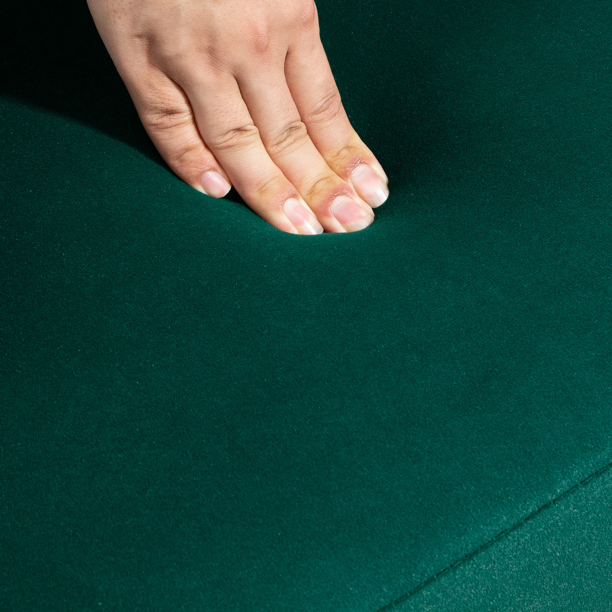 Una mano tocca una superficie verde, forse feltro, su un tavolo.