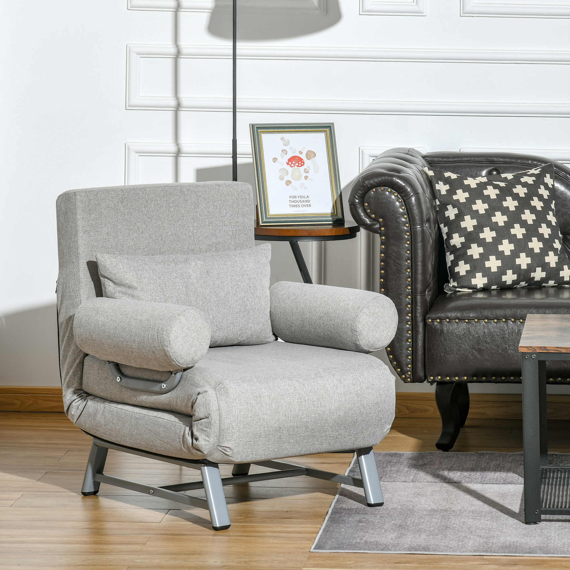 Divano letto grigio convertibile. Una cornice e un divano in pelle sono sullo sfondo.