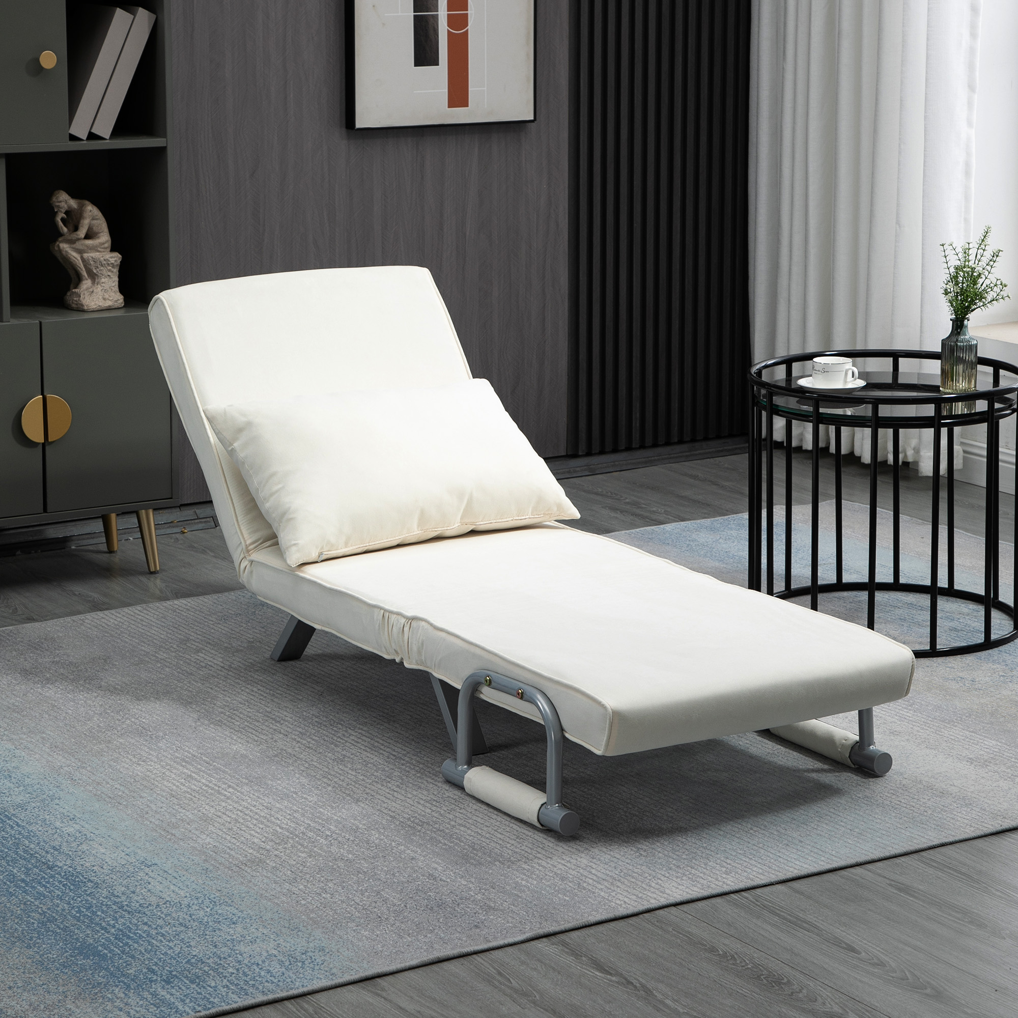 Una chaise longue bianca con un cuscino è su un tappeto vicino a un tavolino nero.