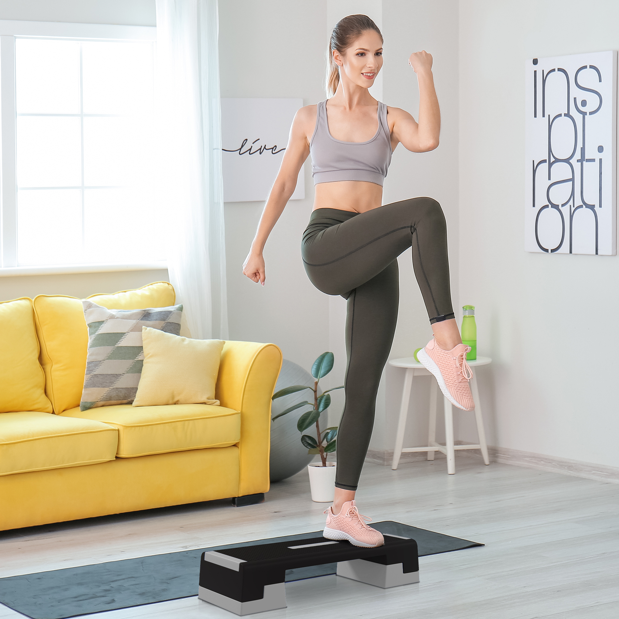 Una donna che fa step aerobica su una piattaforma. È in una sala d'esercizio.