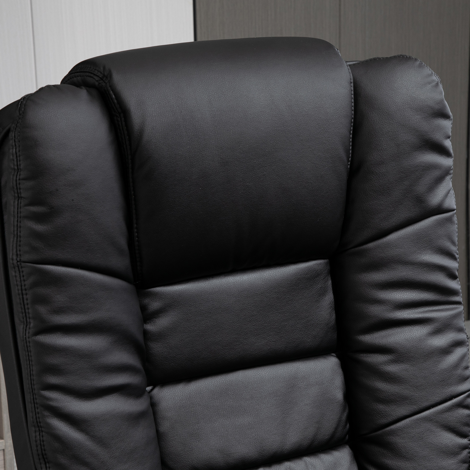 Primo piano del poggiatesta di una sedia da ufficio in pelle nera, che mostra la superficie.