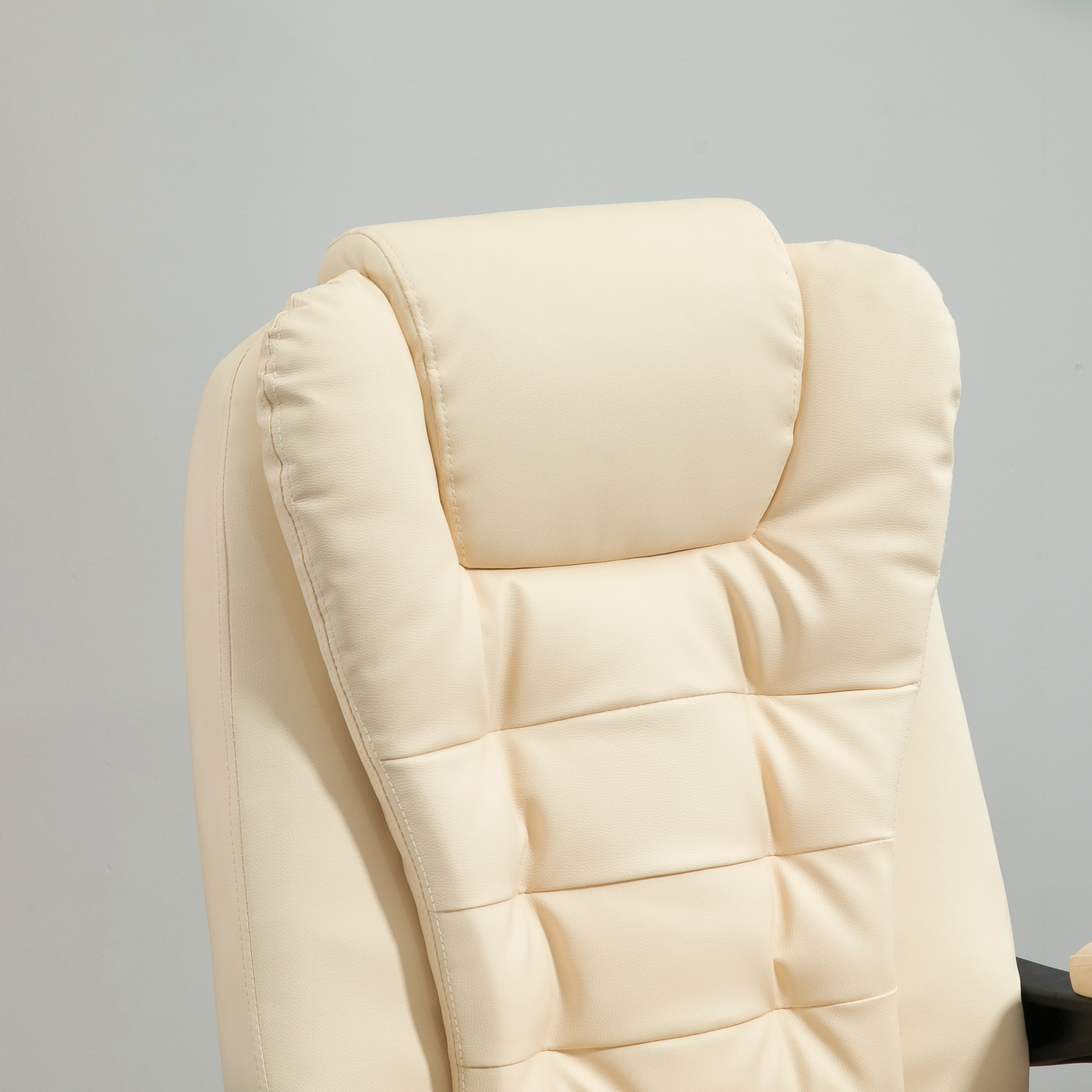 Poggiatesta della sedia da ufficio color crema. Ha un design trapuntato ed è contro un muro grigio.