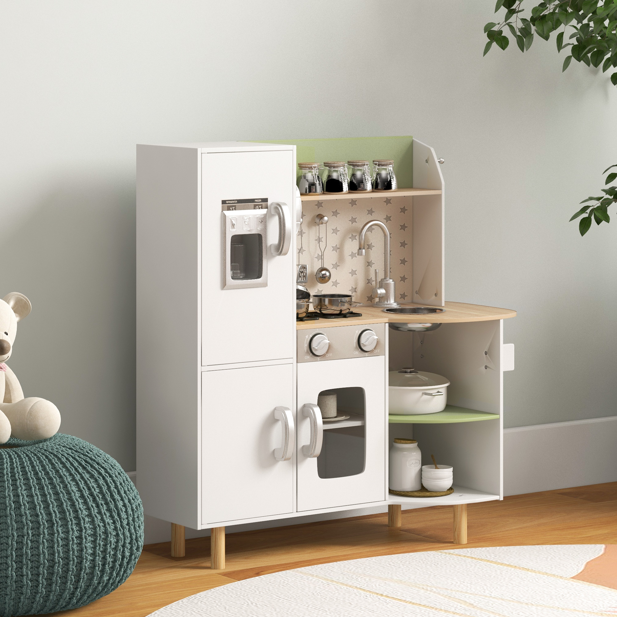 Cucina giocattolo bianca con frigorifero, fornello, lavandino e accessori su superficie verde chiaro.