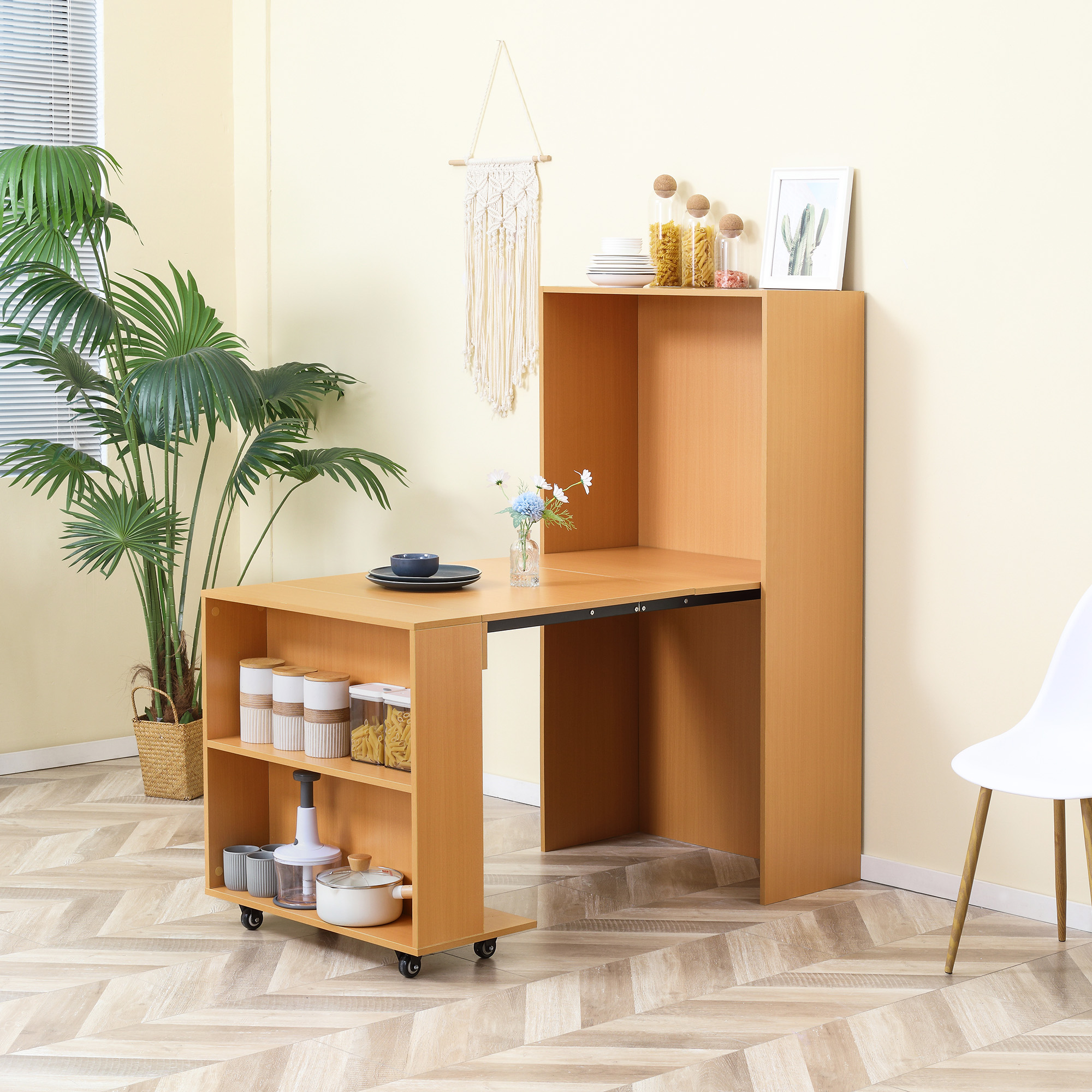 Scrivania pieghevole in legno con ripiani e un arazzo da parete in macramè. Ci sono piante e decorazioni.