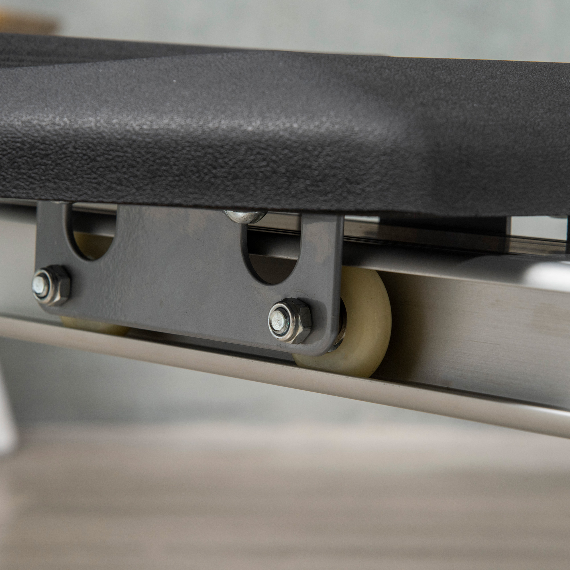 Primo piano di un sistema di binari metallici con bulloni e una ruota rotante in una cornice grigia.