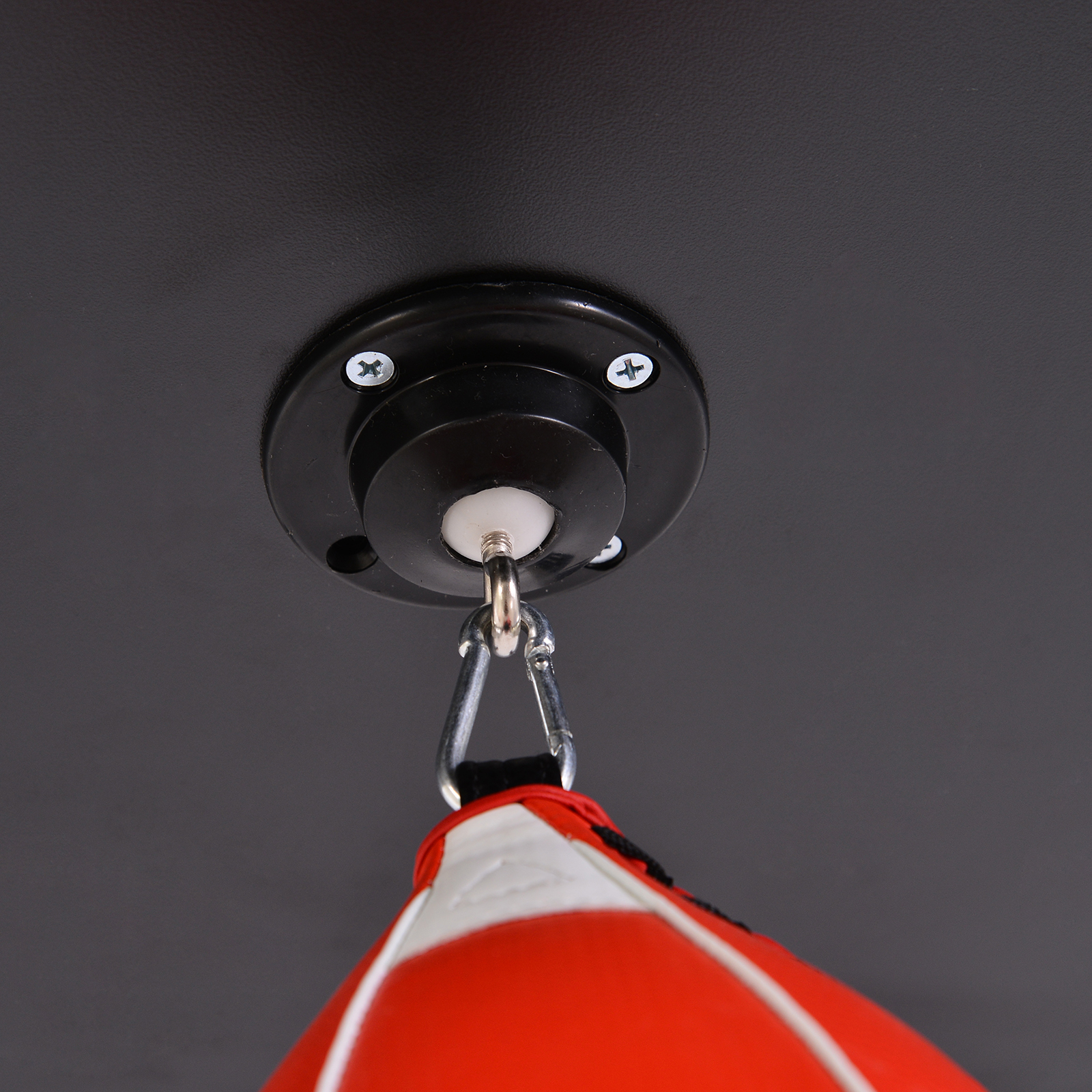 Primo piano di un supporto a soffitto nero con un sacco da boxe rosso e bianco appeso sotto.