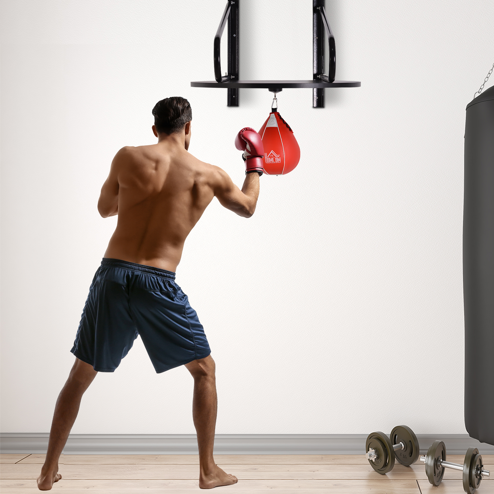 Uomo che boxa un sacco veloce rosso in palestra. Indossa guanti e pantaloncini rossi.