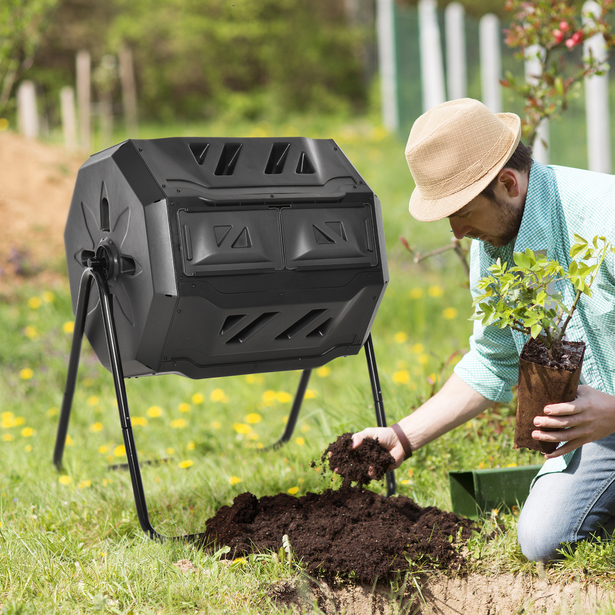 Uomo con cappello che pianta. Contenitore per compost nero sull'erba.