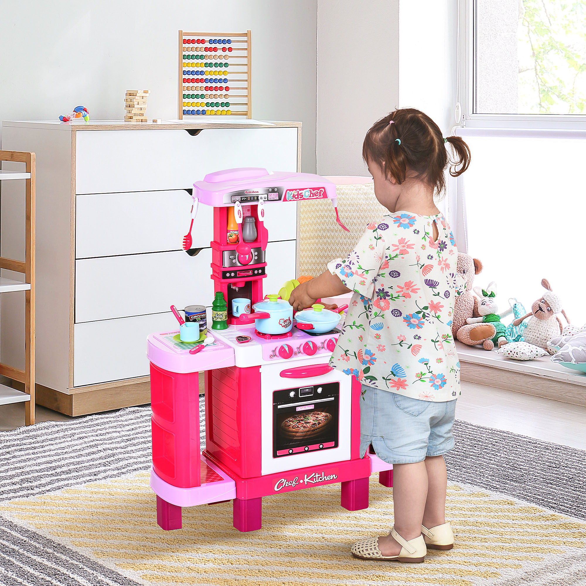 Una bambina gioca con un set da cucina rosa. C'è una torta nel forno.