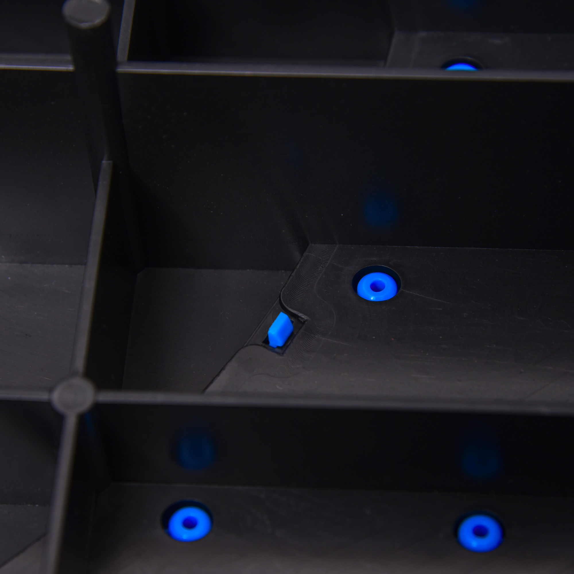 Schwarzes Plastikregal mit blauen Haltern. Mehrere Fächer sichtbar.