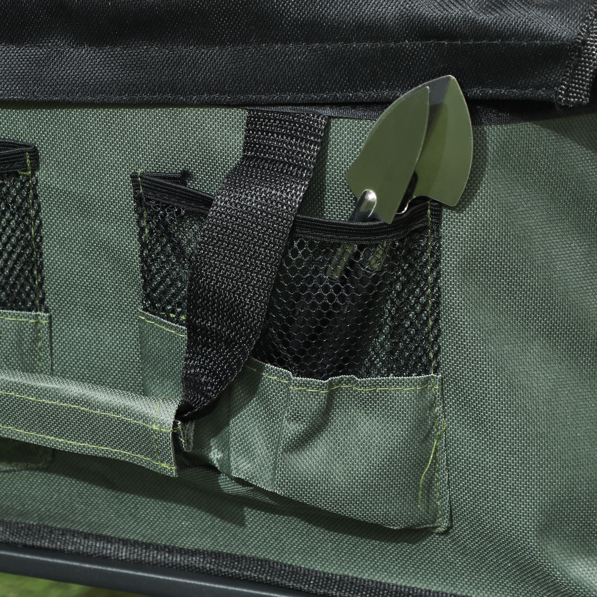 Primo piano di una borsa verde con tasche. Due piccoli attrezzi da giardinaggio in una tasca.