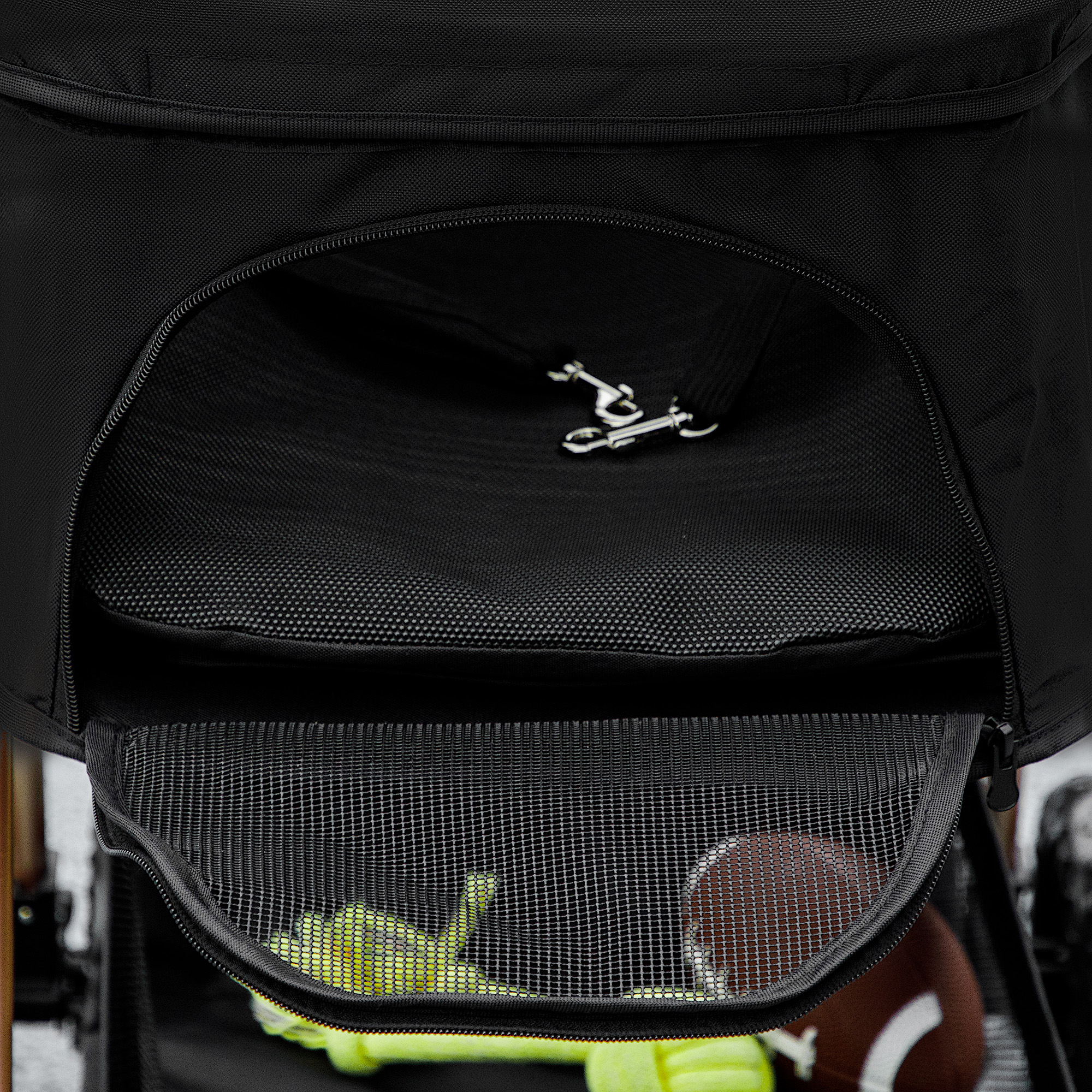 Borsa sportiva nera con scomparti aperti. All'interno, un pallone da football e palline da tennis sono visibili. È presente anche un gancio d'argento.