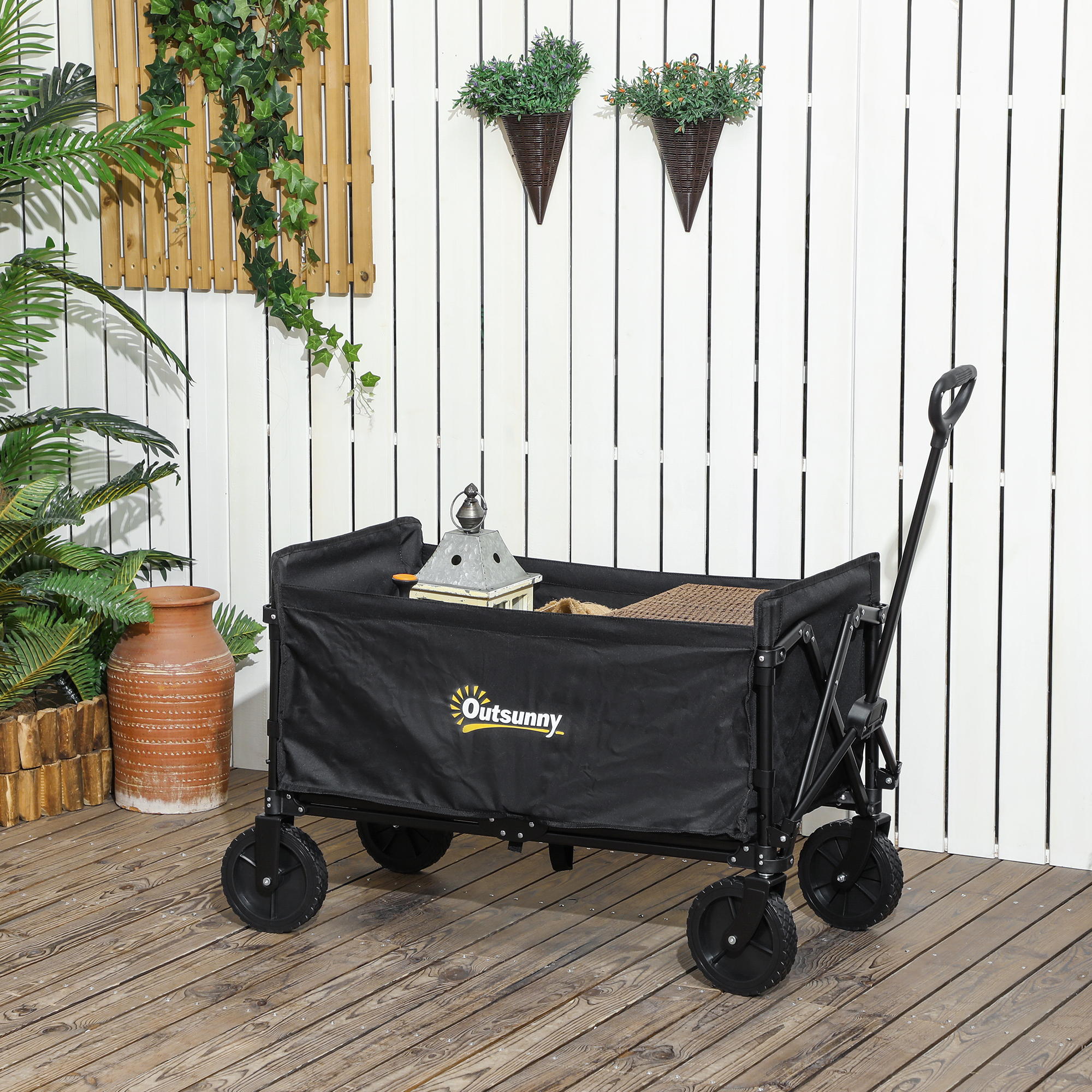 Carrello nero con logo Outsunny su un patio in legno. Parete bianca e piante sospese sullo sfondo.