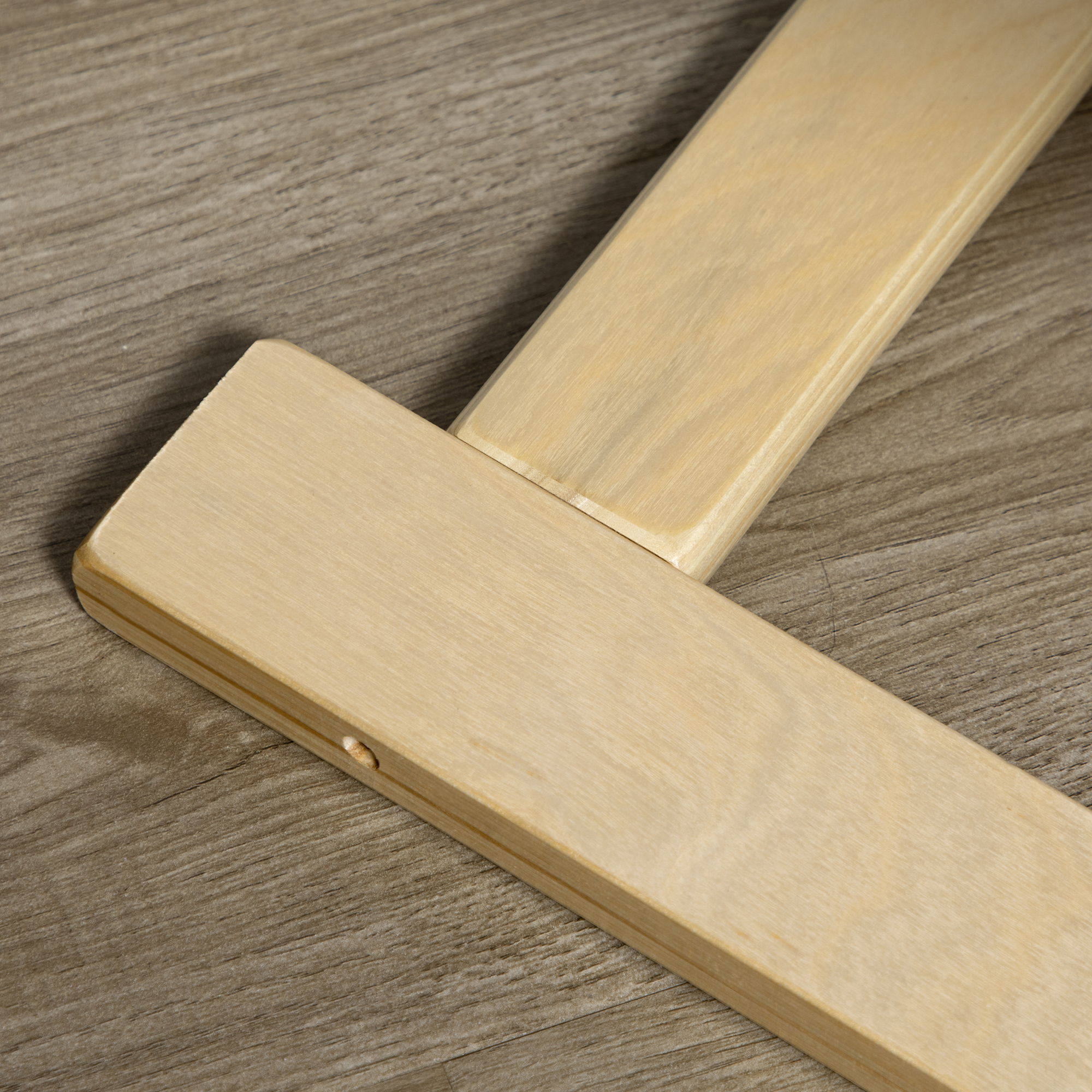 Primo piano di due assi di legno chiaro unite, poste su una superficie di legno grigio.