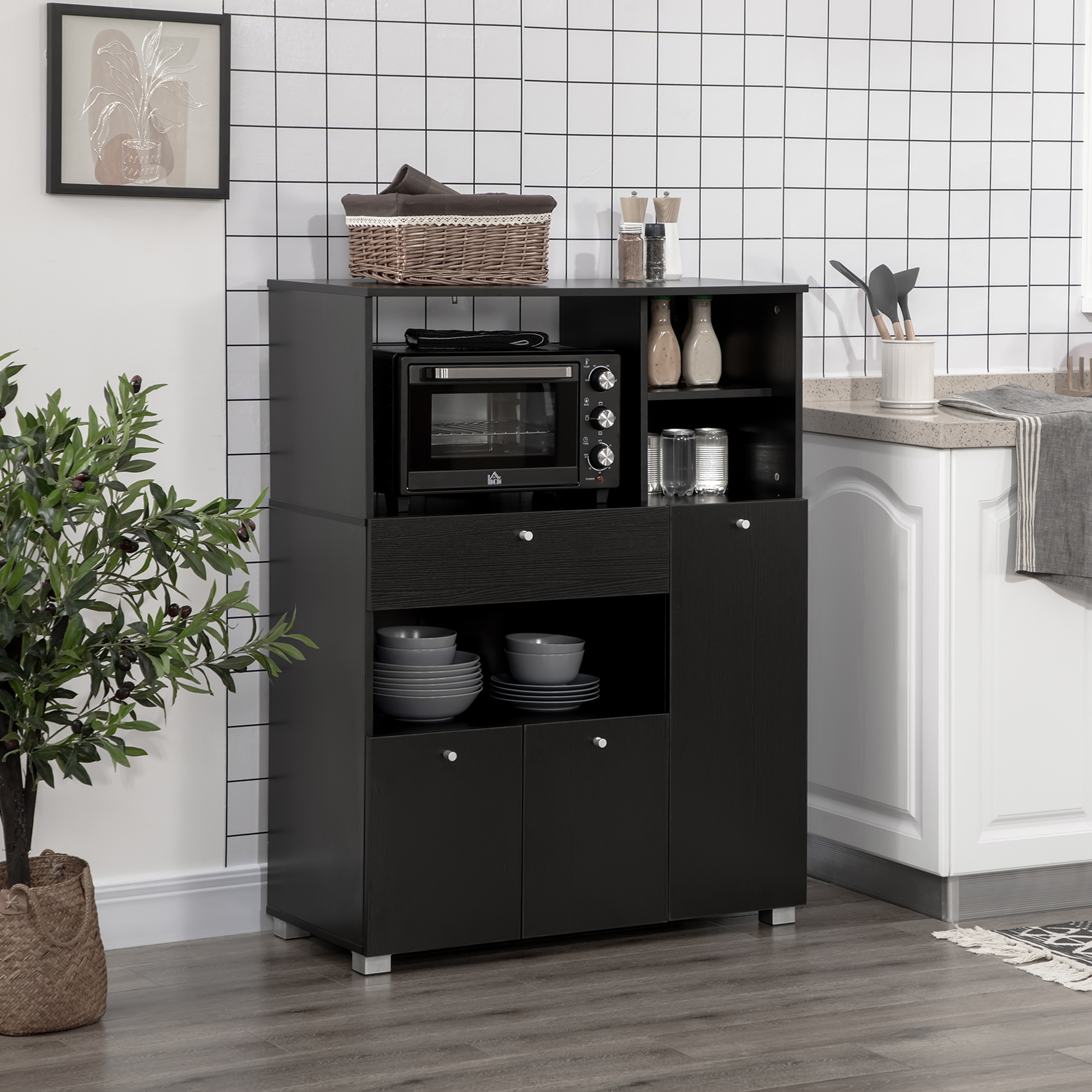 Mobile da cucina nero con forno e stoviglie, contro un muro piastrellato bianco.