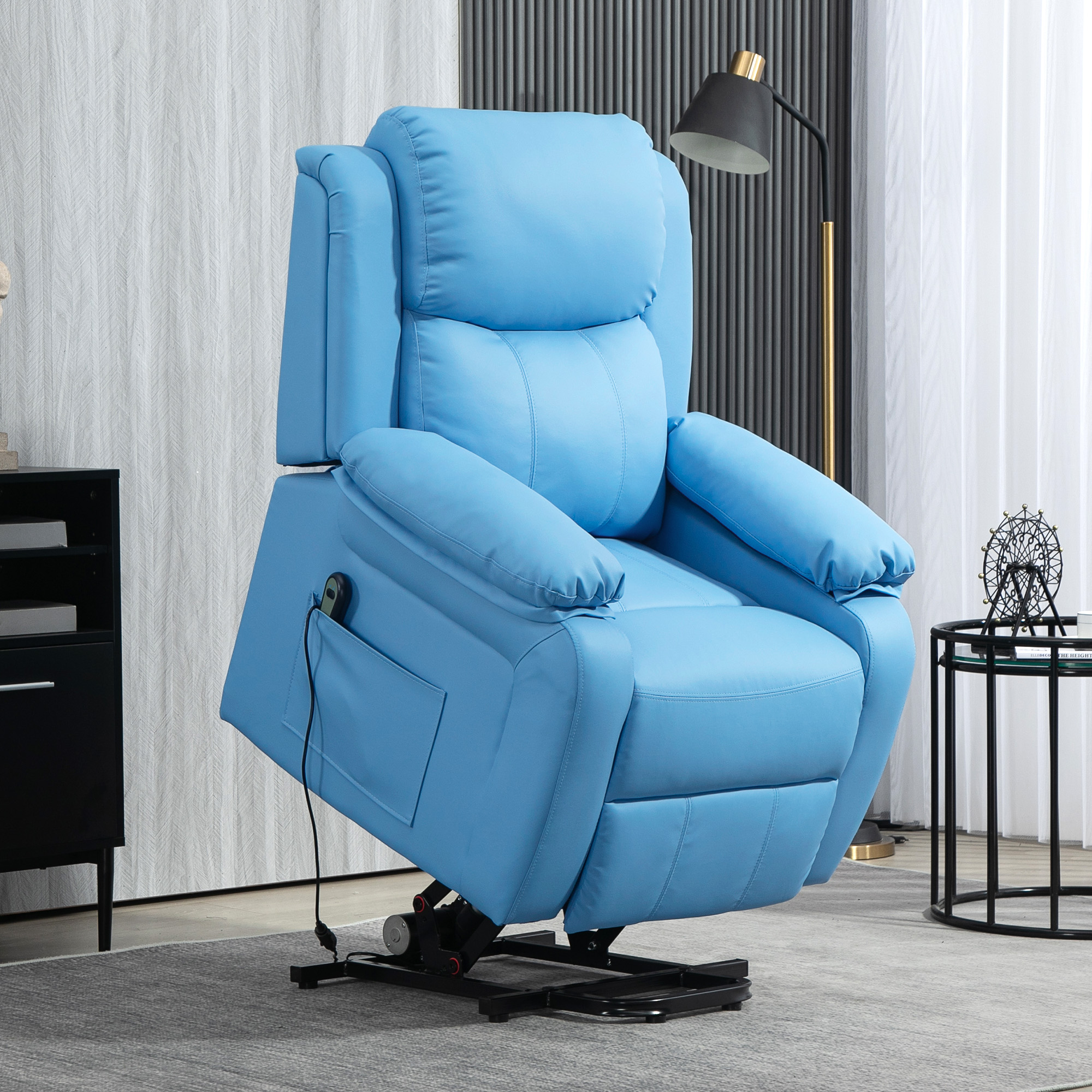Poltrona reclinabile blu su base nera. Lampada nera e tavolino sullo sfondo.