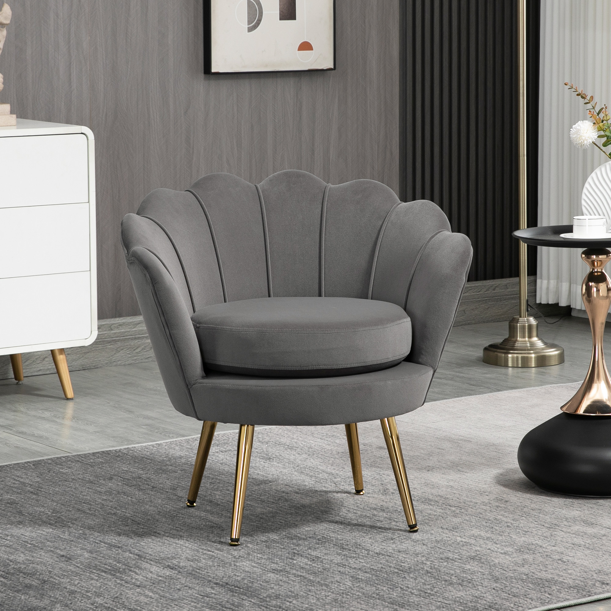 Una sedia in velluto grigio con gambe dorate, posizionata su un tappeto grigio.