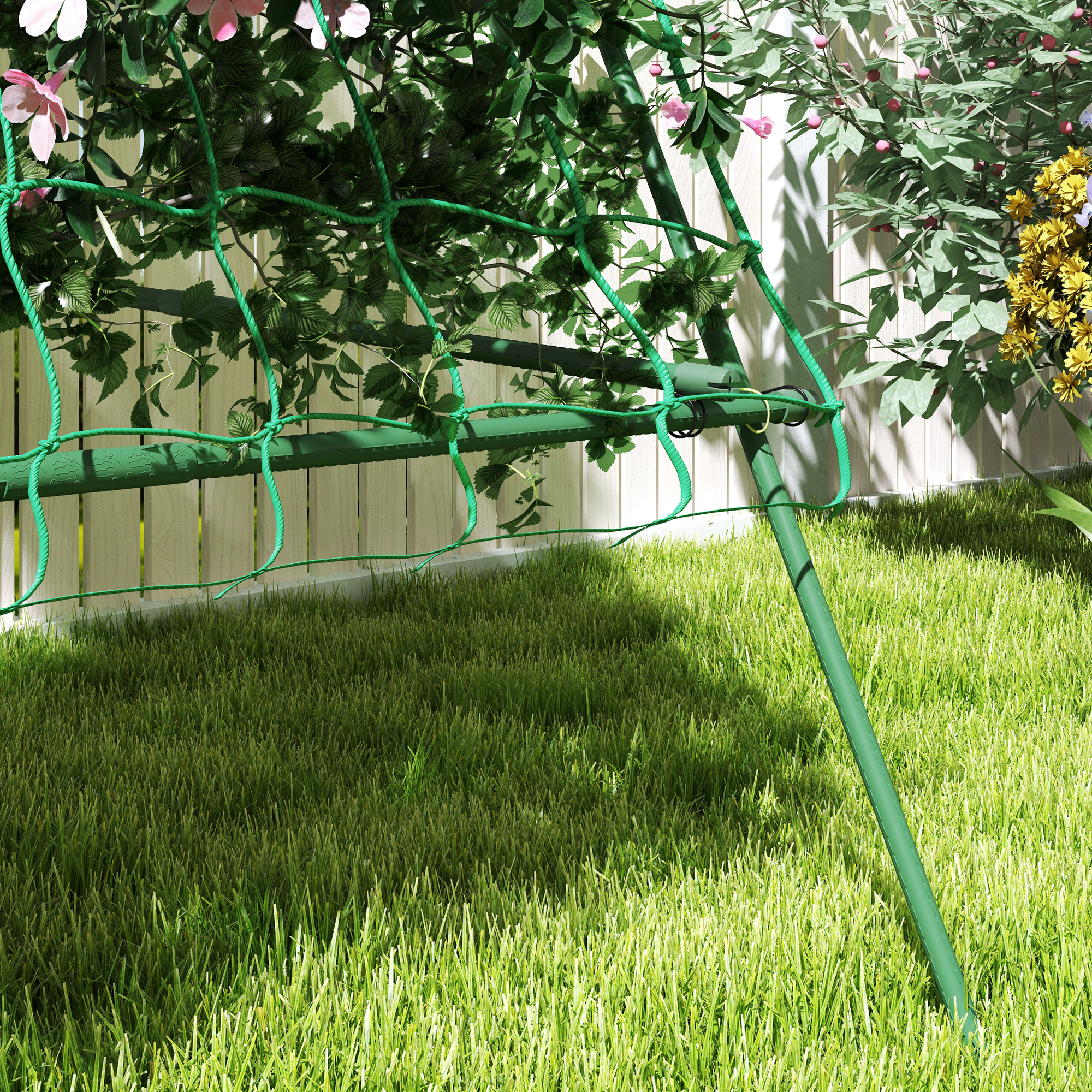 Una recinzione a rete verde in un giardino erboso con fiori.