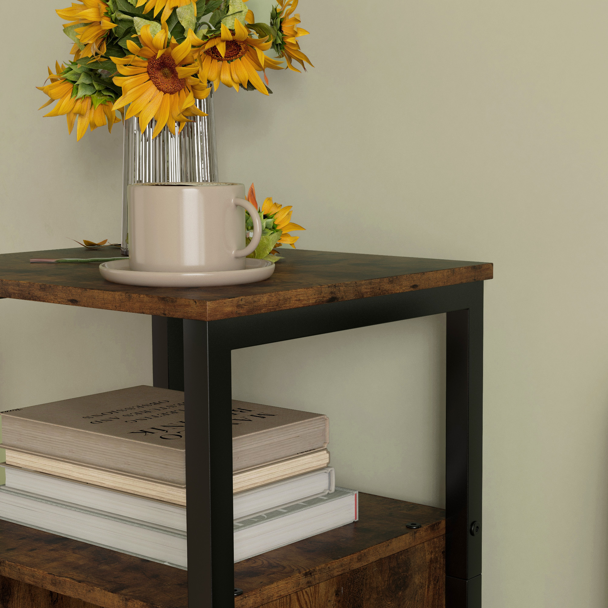 Tavolino con libri, tazza e girasoli in un vaso, contro un muro.