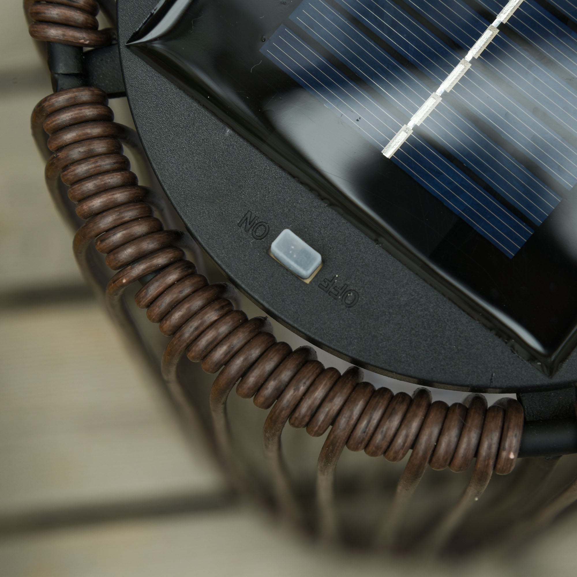 Eine Solar-Gartenleuchte. Sie hat ein braunes, gewickeltes Design und einen Ein-/Ausschalter.