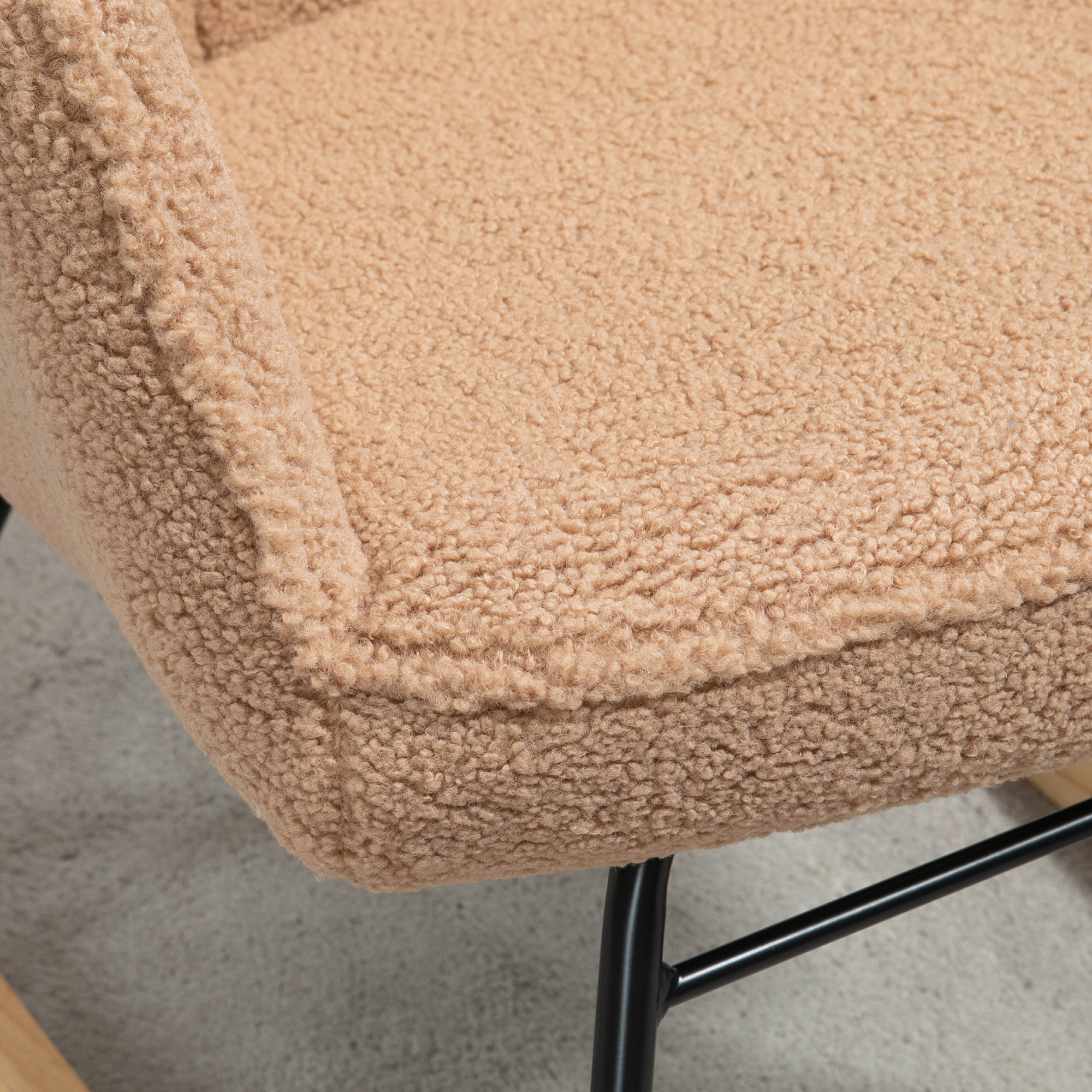 Primo piano di una sedia beige e soffice. Il materiale è strutturato e morbido, con una struttura scura sotto.