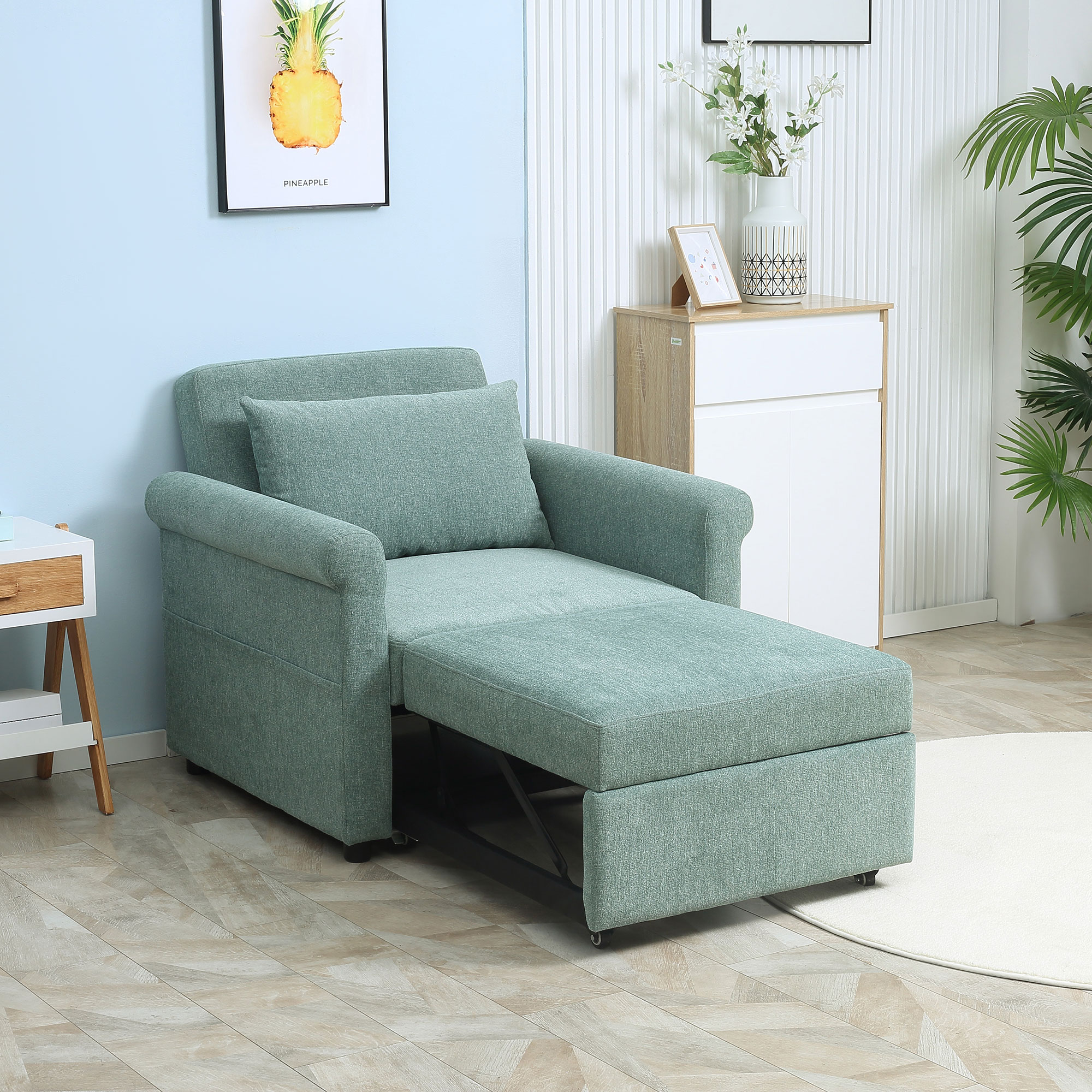 Un divano verde che si trasforma in un letto con un pouf. Un cassetto bianco sullo sfondo.