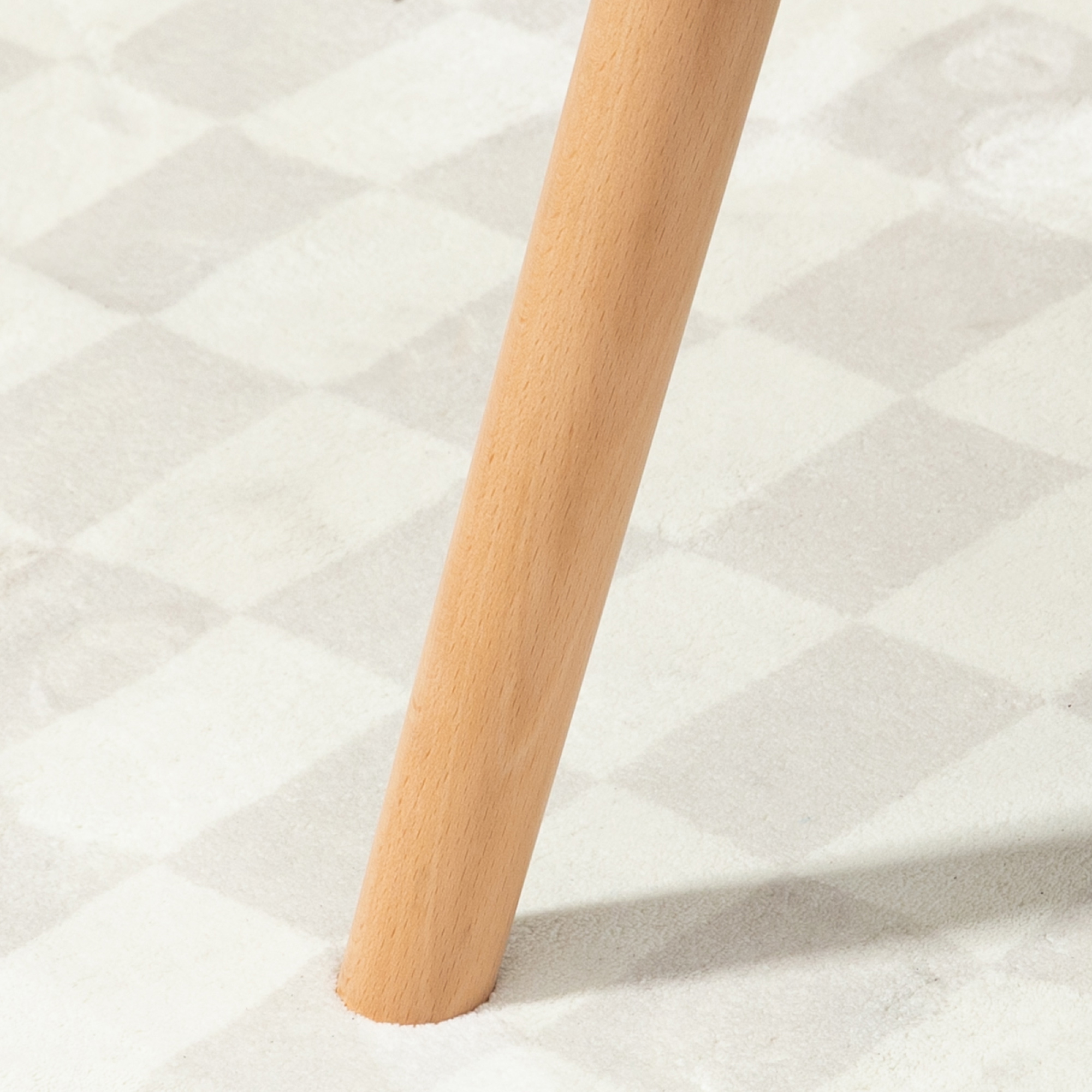 Una gamba di legno di un mobile su una superficie chiara a fantasia.