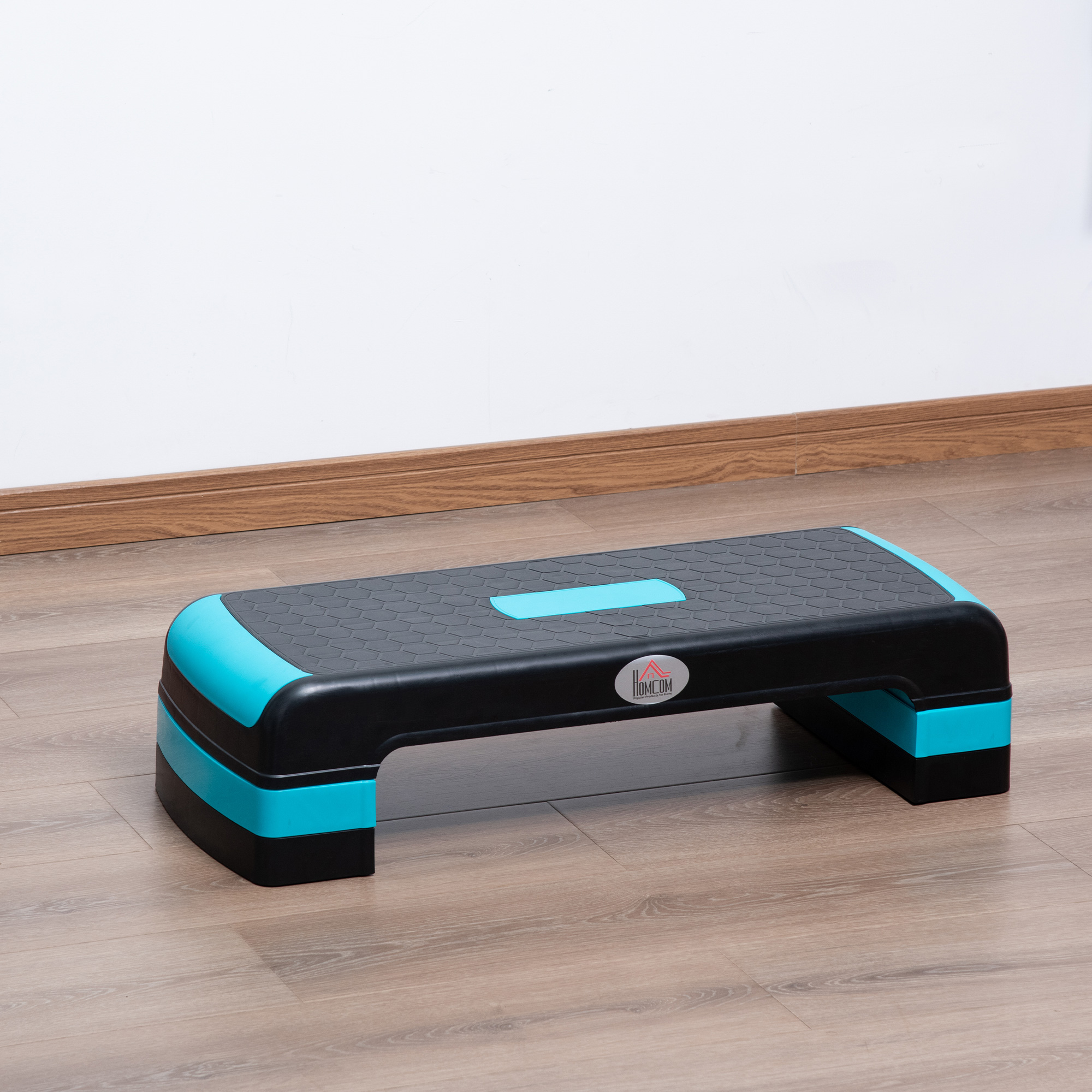 Piattaforma per gradini nera e blu. Su un pavimento in legno, con un muro bianco sullo sfondo.