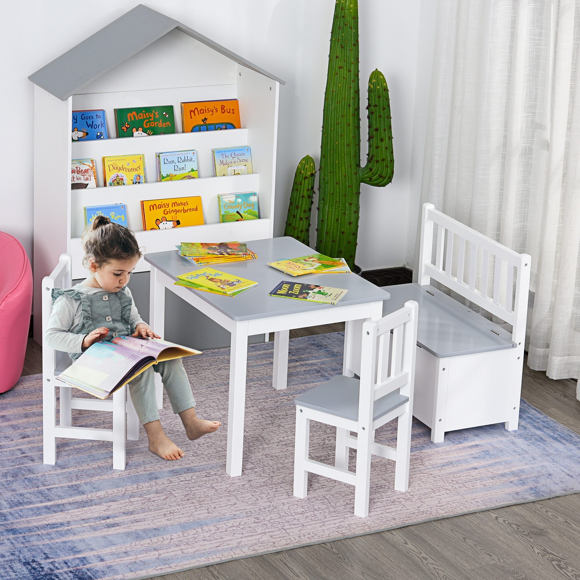 Una bambina è seduta a un tavolo con dei libri. Nella stanza ci sono una libreria, un tavolo, due sedie e una panca.