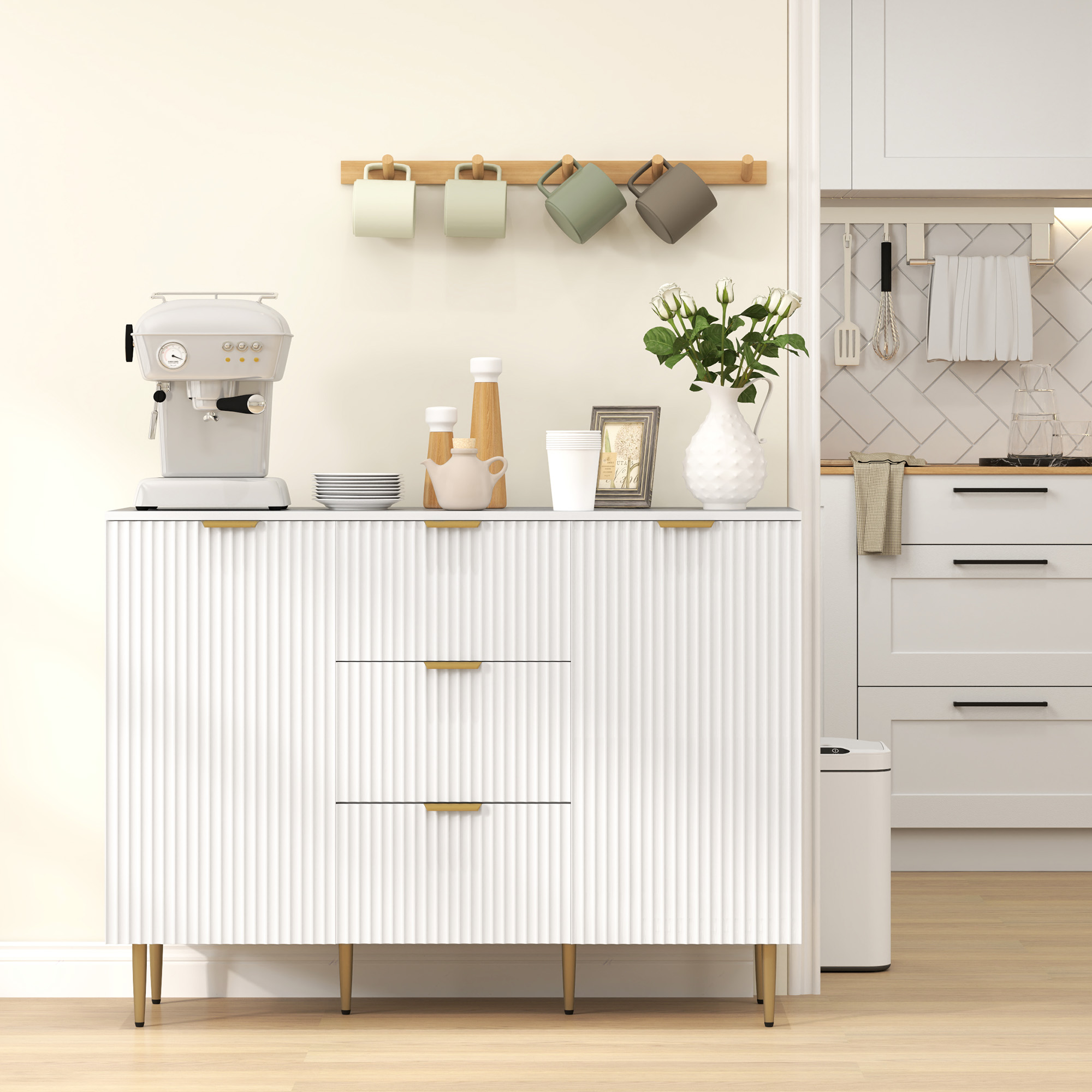 Mobile da cucina bianco con maniglie dorate. Ha cassetti e un piano di lavoro con oggetti.