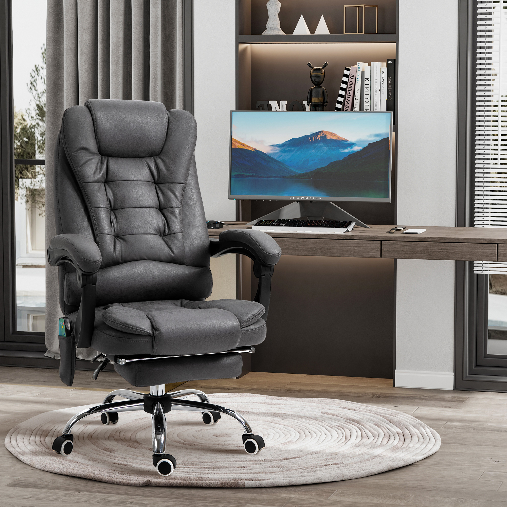 Una sedia da ufficio grigia con poggiapiedi è centrata. Sullo sfondo una scrivania con monitor e una libreria.