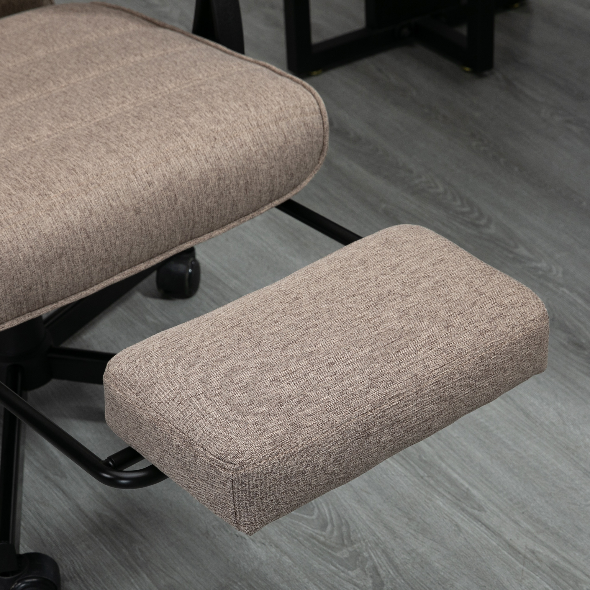 Sedia ergonomica color cuoio con poggiagambe. Sedia su pavimento in legno grigio.